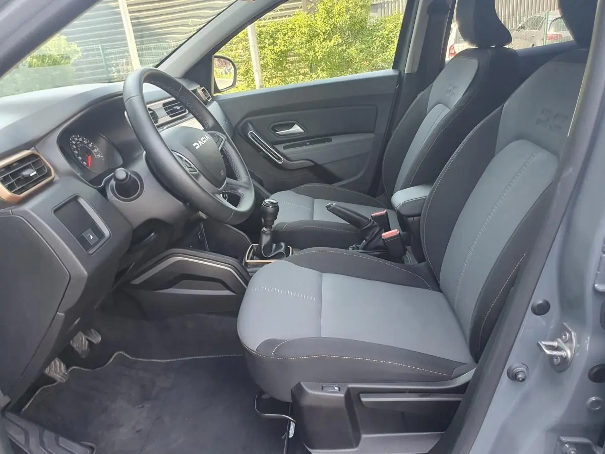Vue intérieure côté conducteur du Dacia Duster 1.5 DCI 115 Extreme 4x4 gris urbain, sièges bi-ton et volant multifonction.