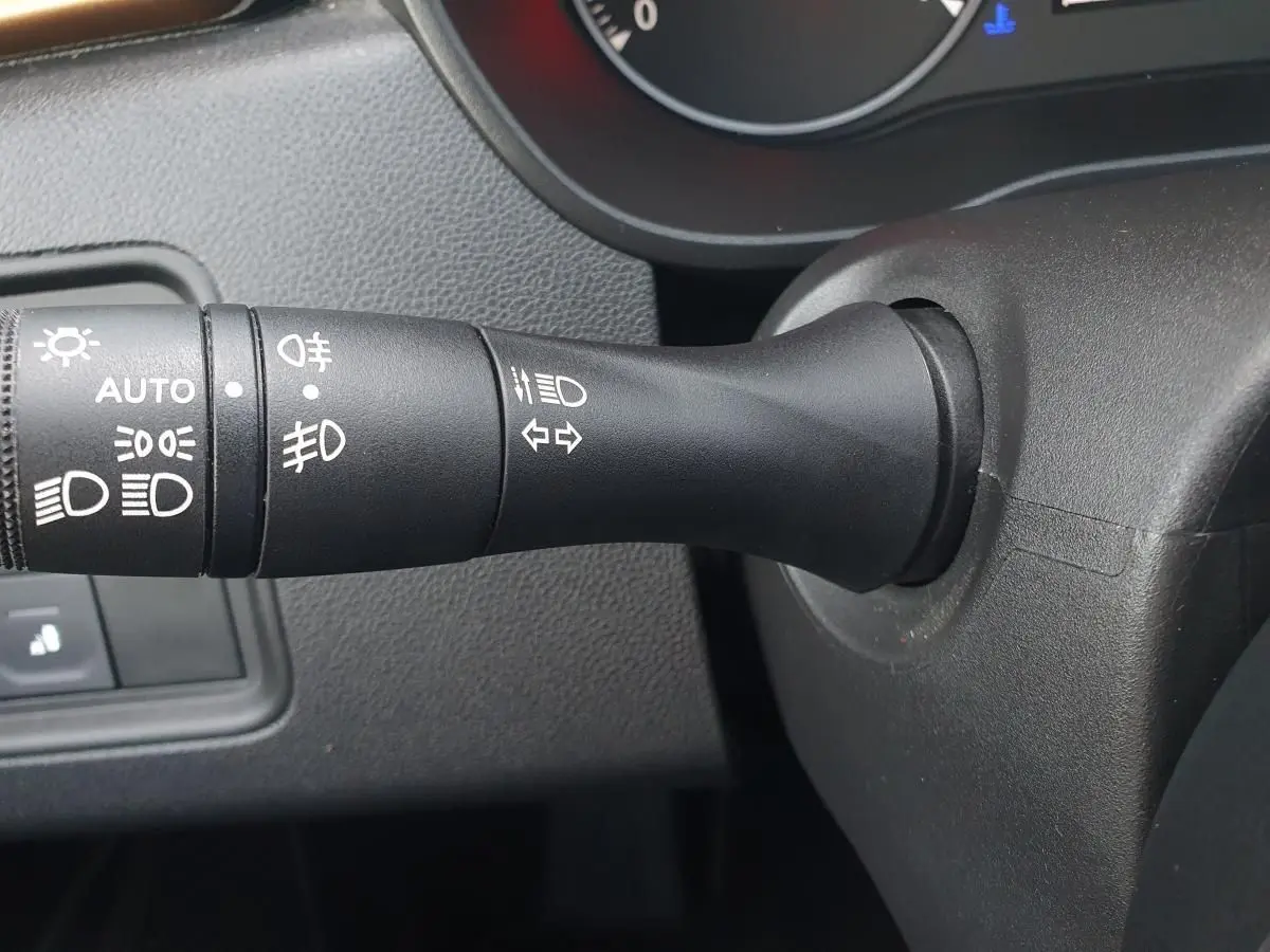 Gros plan sur la commande des feux et clignotants à gauche du volant dans l'habitacle du Dacia Duster 2023.