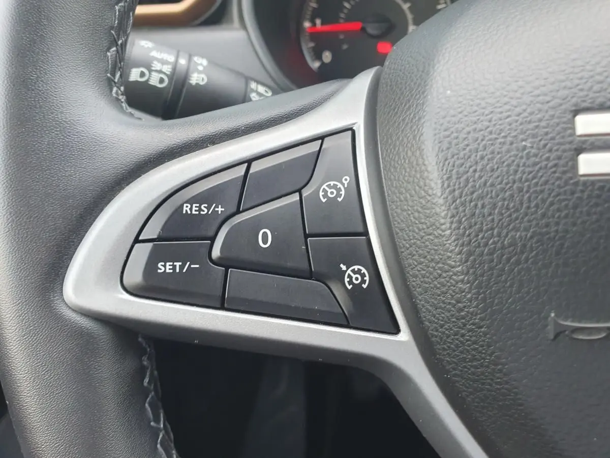 Gros plan sur les commandes du régulateur de vitesse au volant du Dacia Duster 2023, finition Extreme.