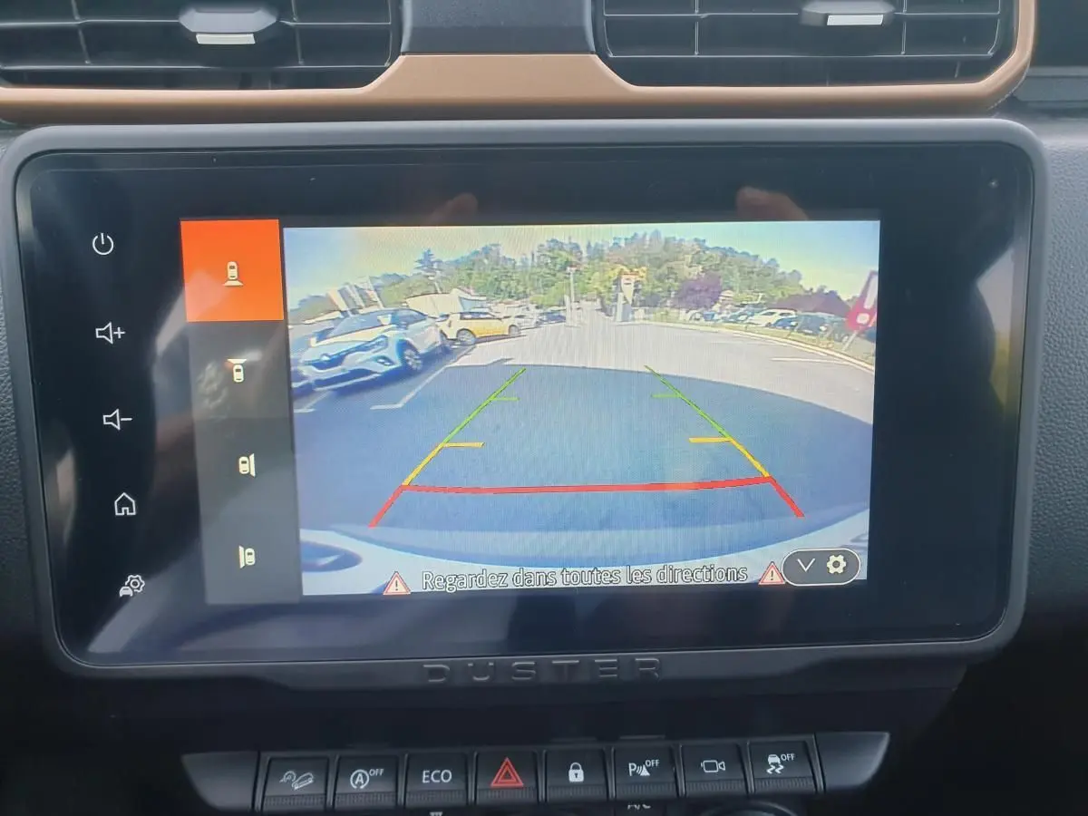 Écran central du Dacia Duster 2023 montrant la caméra 360 en marche, avec vue arrière du parking.