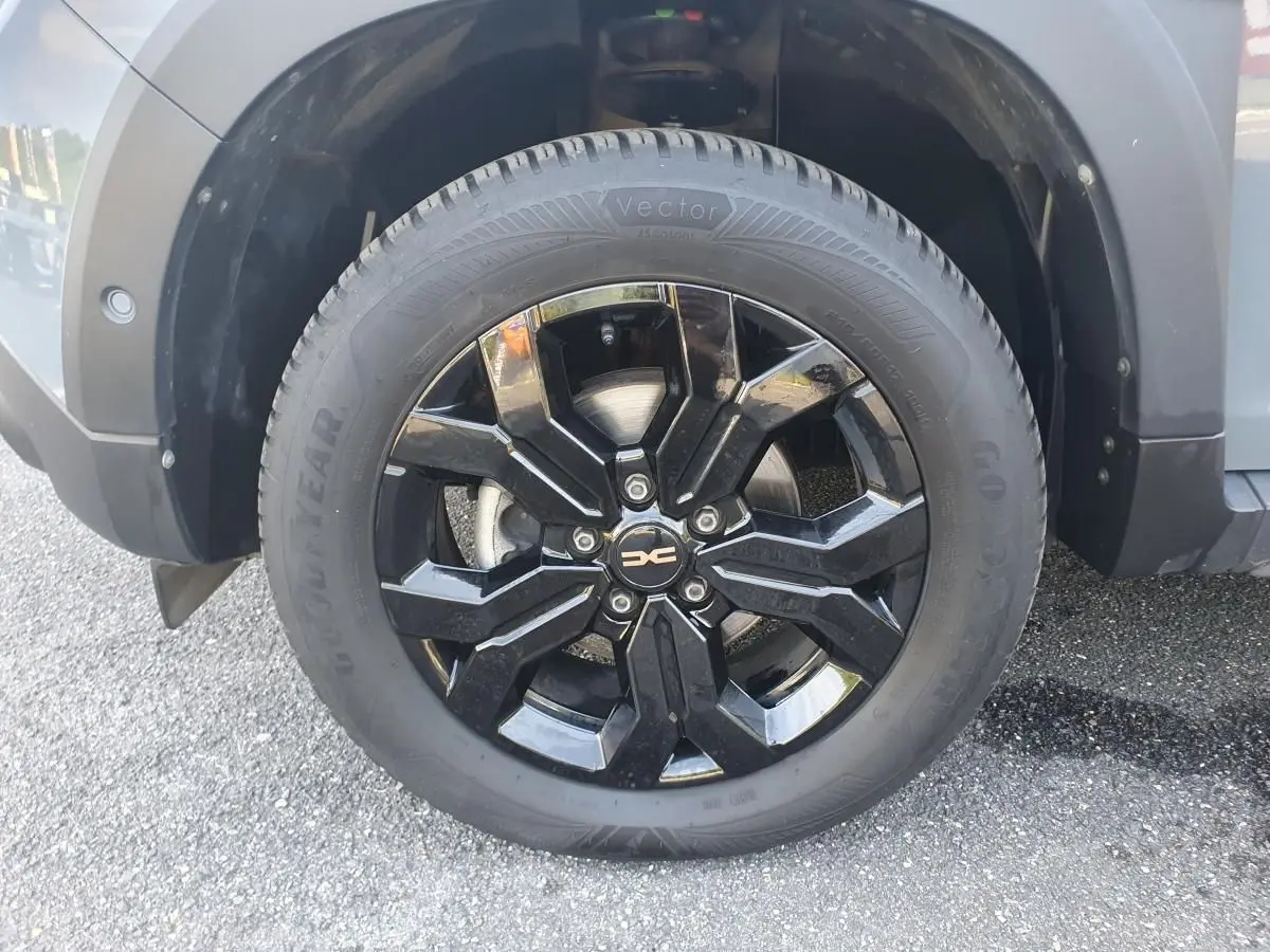 Gros plan sur la roue avant droite du Dacia Duster gris urbain, jante noire brillante au design moderne.
