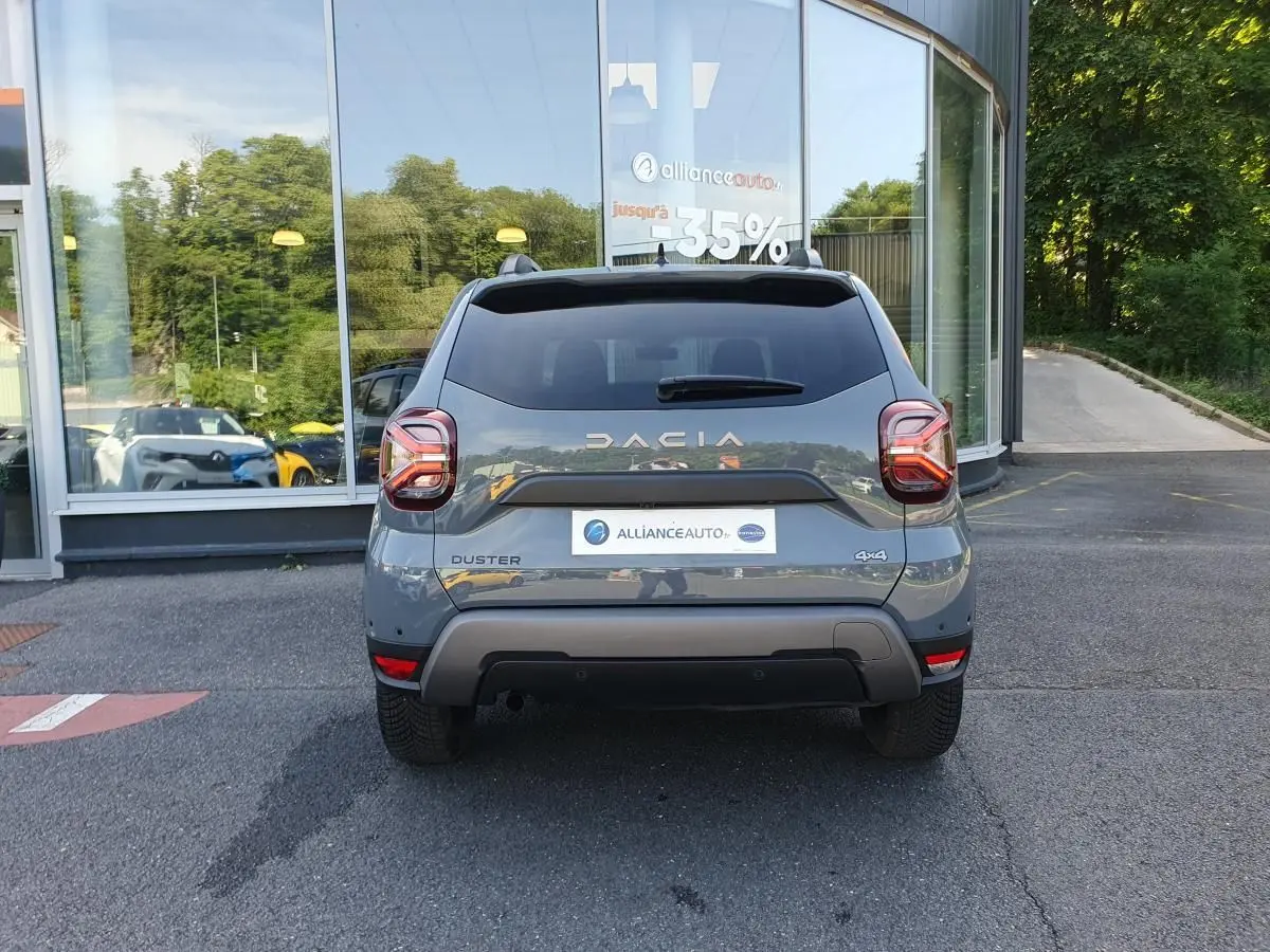 Vue arrière d'un Dacia Duster gris urbain 2023 avec logo DACIA et badge 4x4 visible sur un parking.