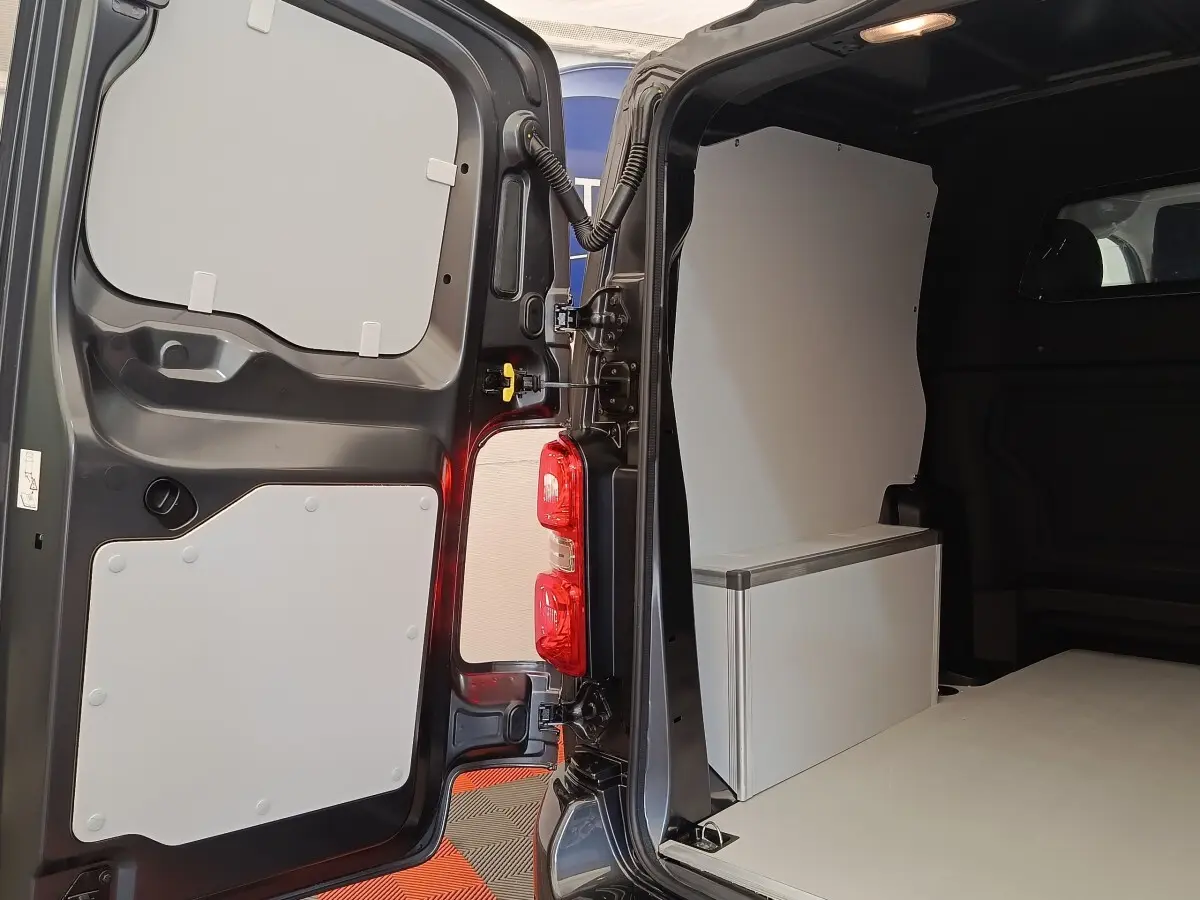 Vue arrière ouverte du Citroën Jumpy gris foncé 2025, montrant l'intérieur utilitaire avec cloison pleine et rangement blanc.