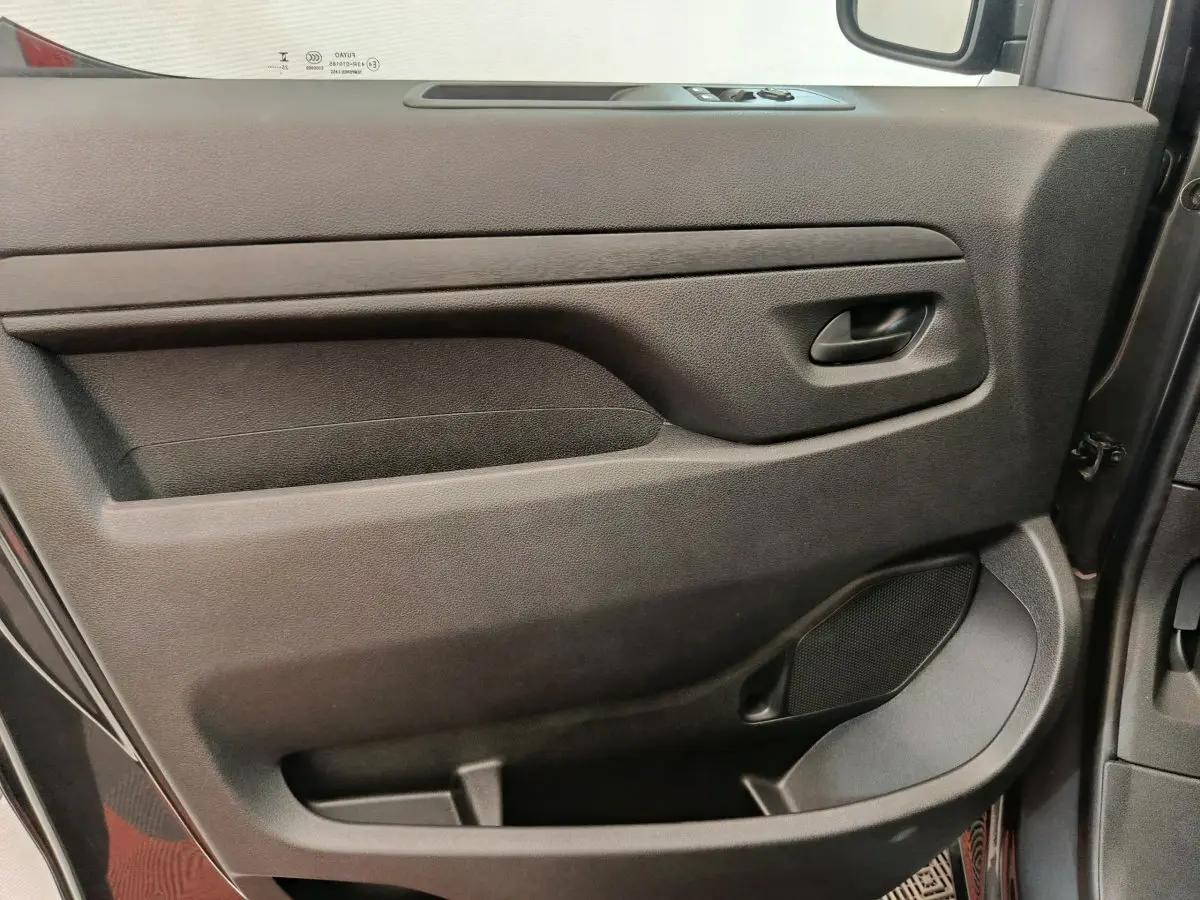 Vue rapprochée de la porte côté conducteur du Citroën Jumpy gris foncé, montrant la poignée et les commandes des vitres.