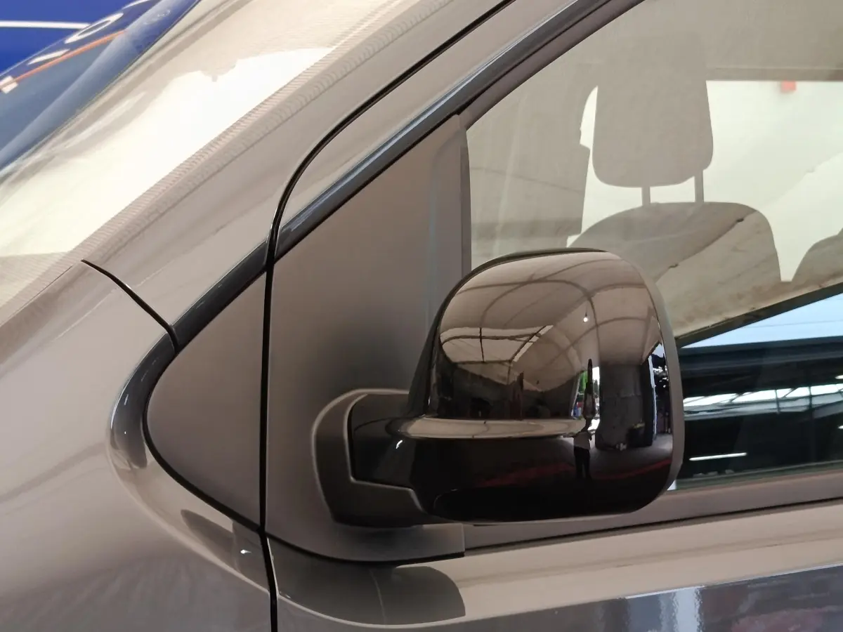 Gros plan sur le rétroviseur droit noir du Citroën Jumpy gris foncé, avec reflet de l'environnement intérieur.