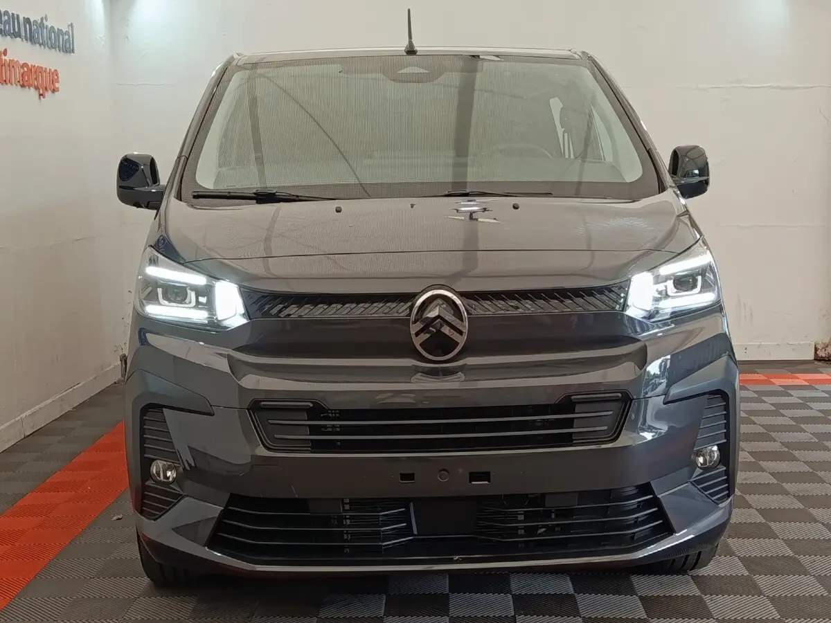 Vue frontale d'un Citroën Jumpy gris foncé 2025 avec phares LED allumés dans un showroom.