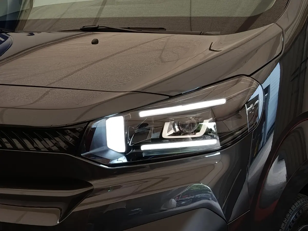 Gros plan sur le phare avant droit allumé du Citroën Jumpy gris foncé 2025, mettant en valeur sa signature lumineuse LED.