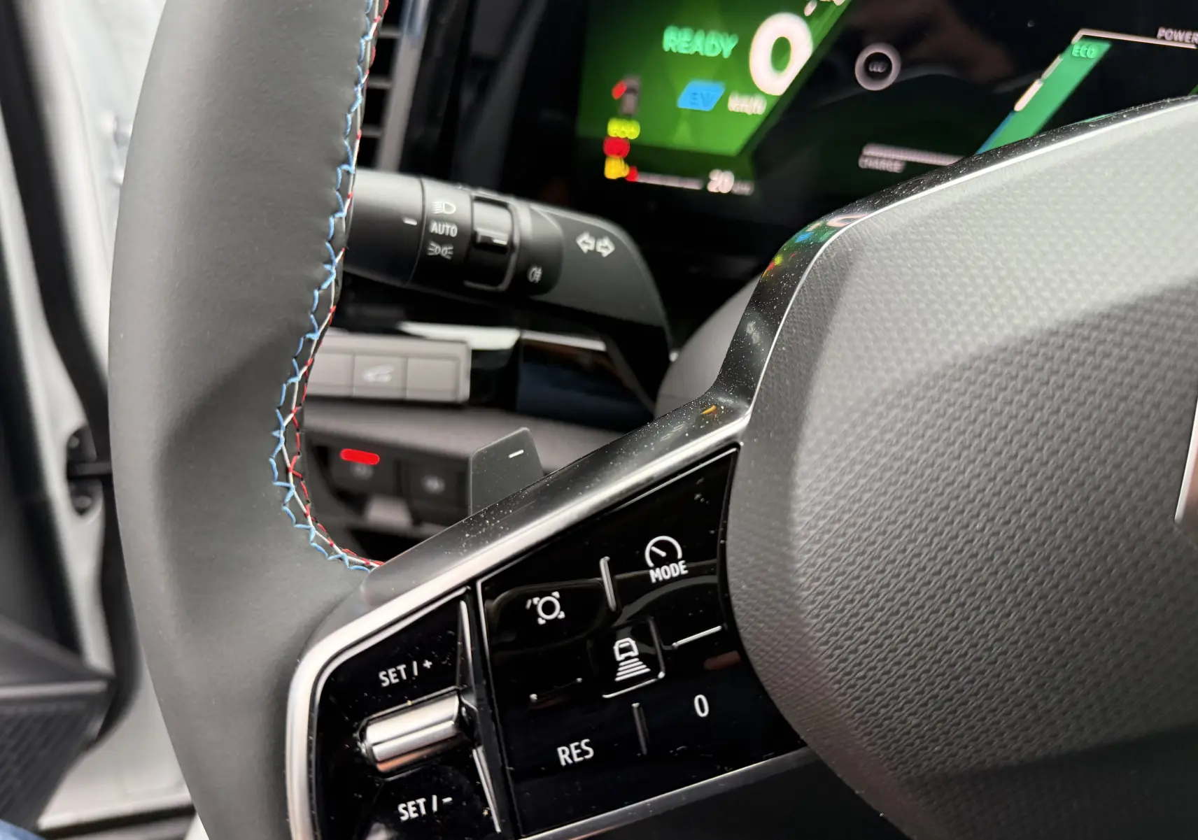 Gros plan sur le volant avec commandes intégrées et tableau de bord numérique allumé du Renault Austral blanc nacré.