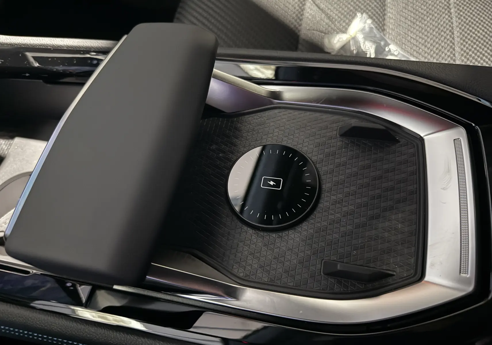 Vue rapprochée de la console centrale noire du Renault Austral Esprit Alpine, avec un espace de recharge sans fil et accoudoir rembourré.