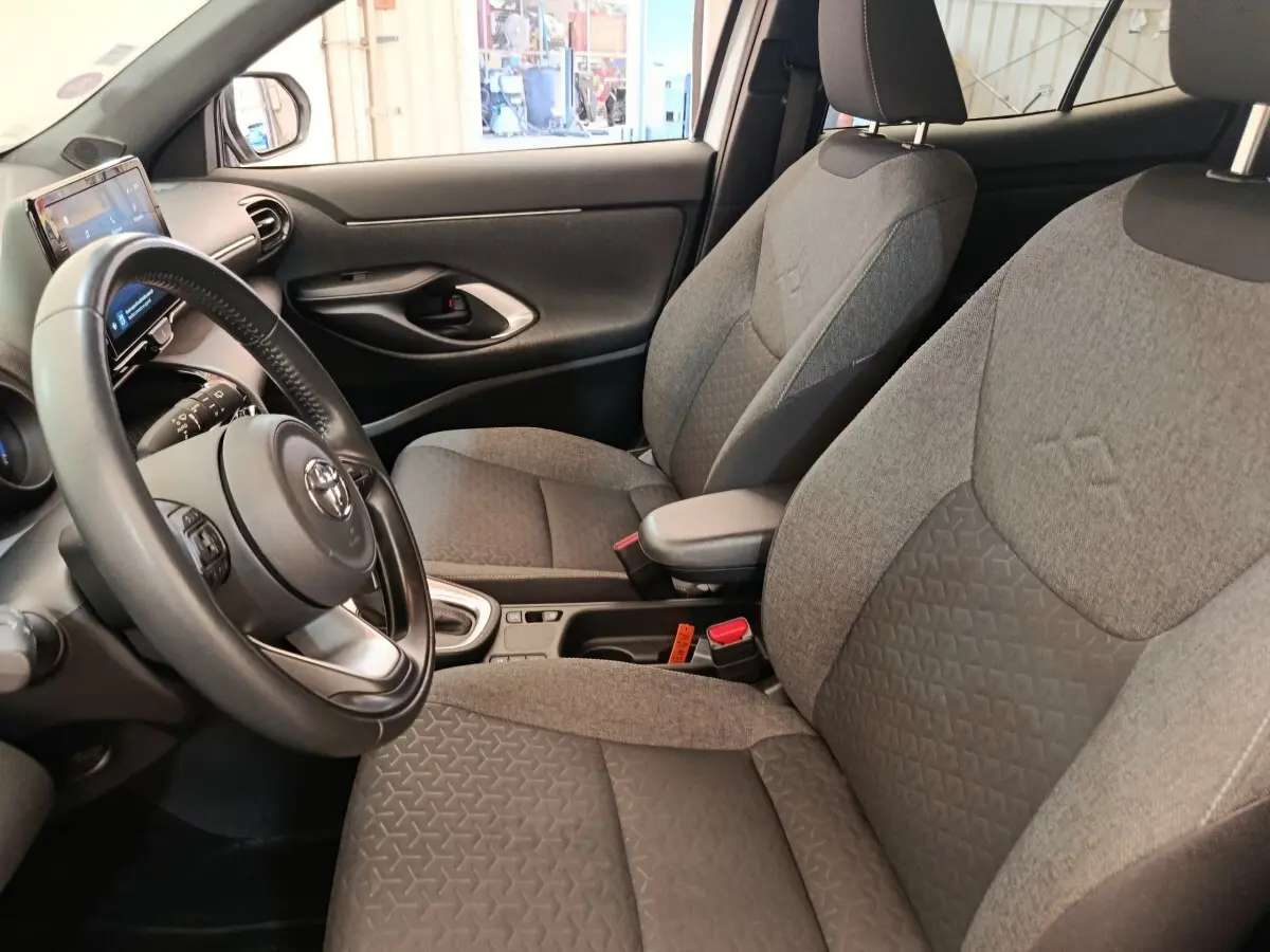 Vue intérieure côté conducteur de la Toyota Yaris Cross 1.5 Hybrid 116h, sièges gris et volant cuir multifonctions.