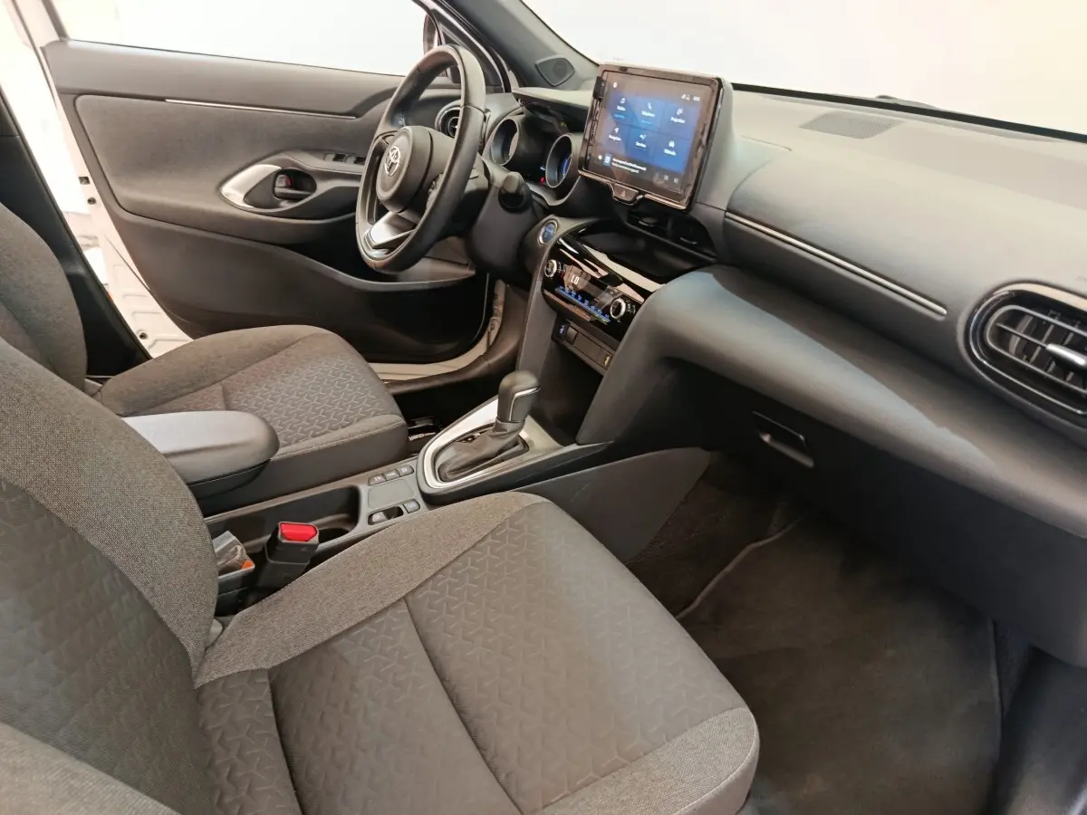 Vue intérieure côté conducteur de la Toyota Yaris Cross blanche 2022, avec tableau de bord et écran tactile central.