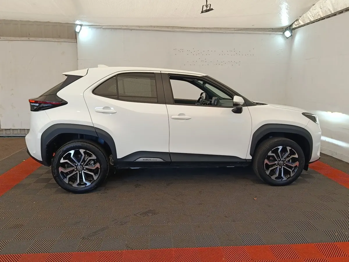 Profil droit d'une Toyota Yaris Cross blanche 2022 avec jantes alliage noires et détails noirs sur les bas de caisse.