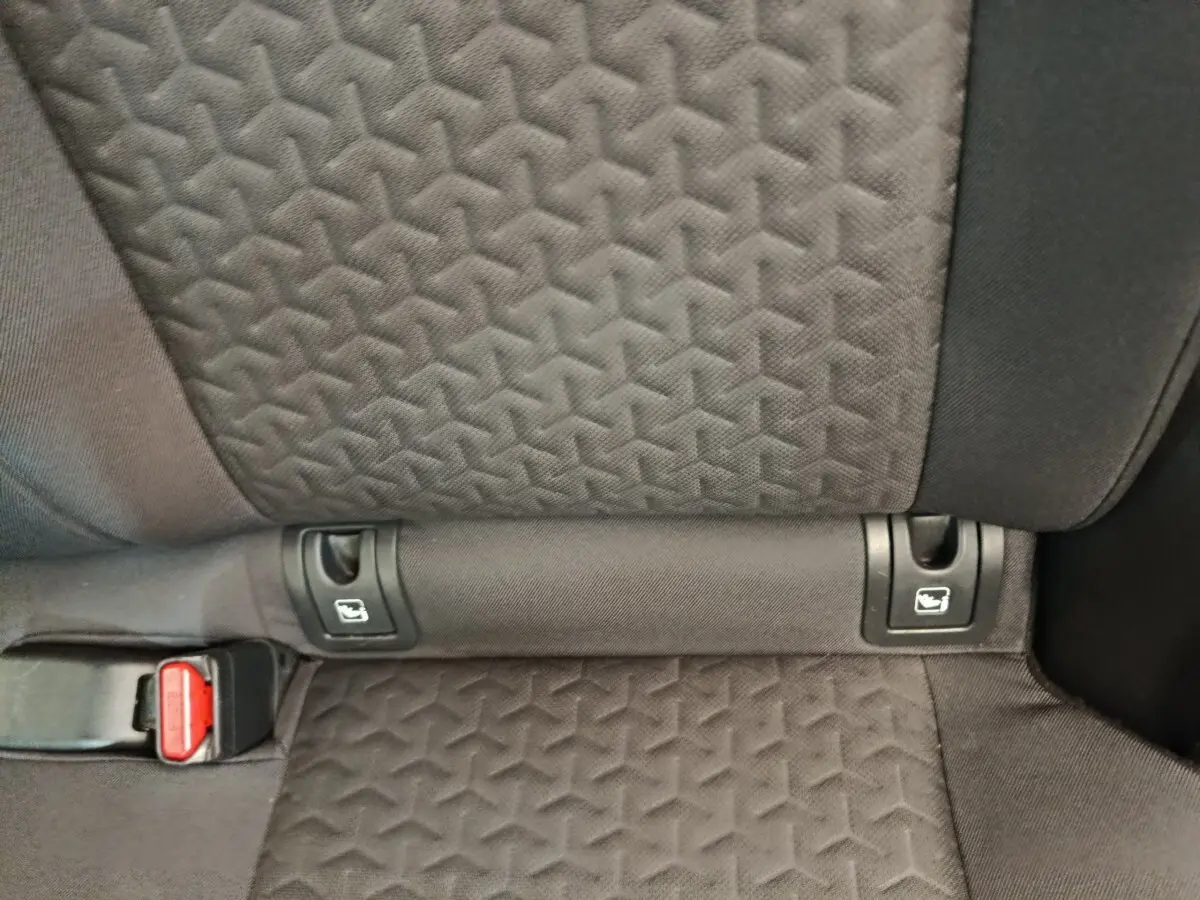 Détail de la banquette arrière noire de la Toyota Yaris Cross avec fixation Isofix et boucle de ceinture rouge visible.