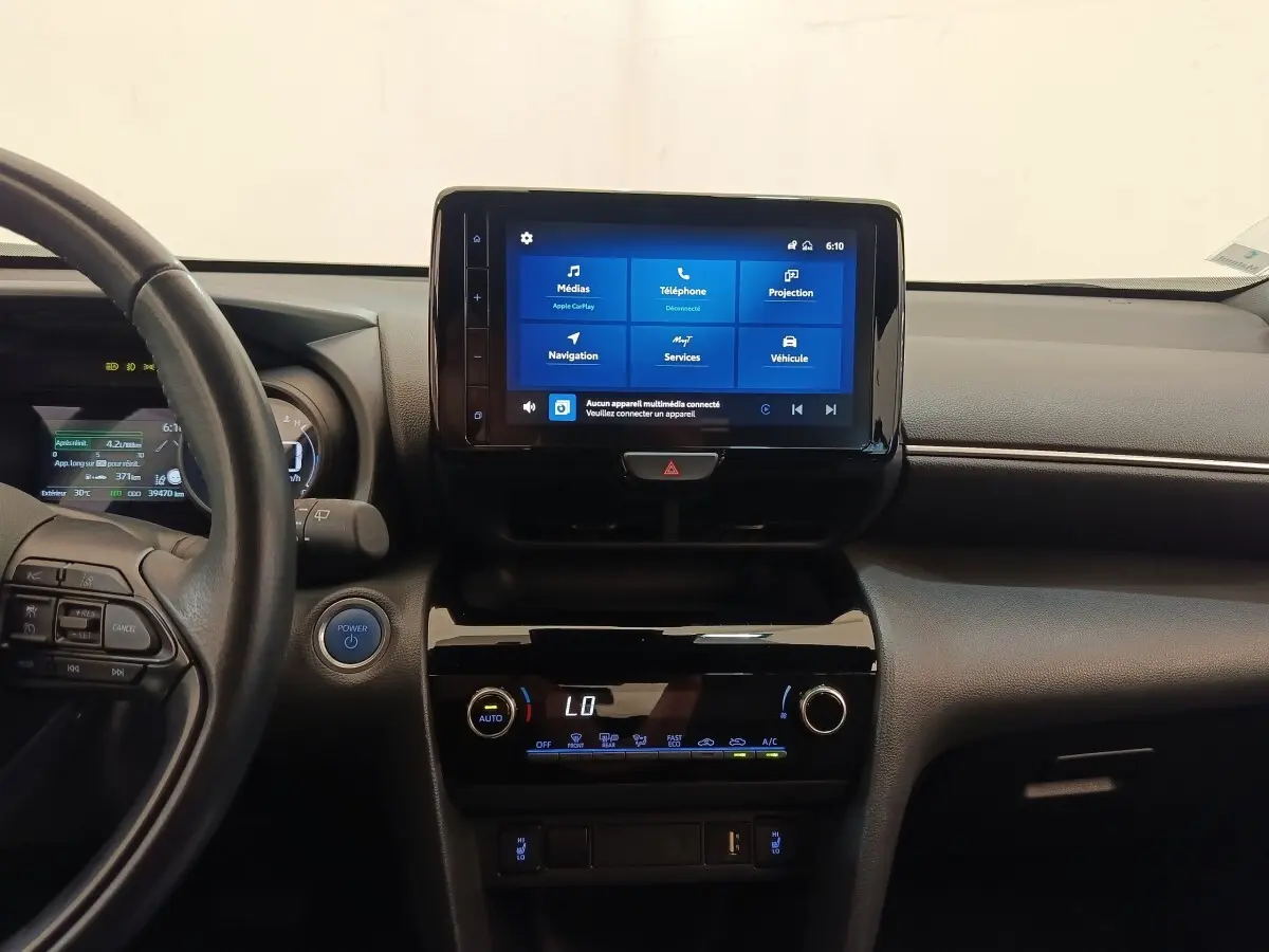 Vue intérieure centrée sur le tableau de bord noir de la Toyota Yaris Cross hybride avec écran tactile allumé.