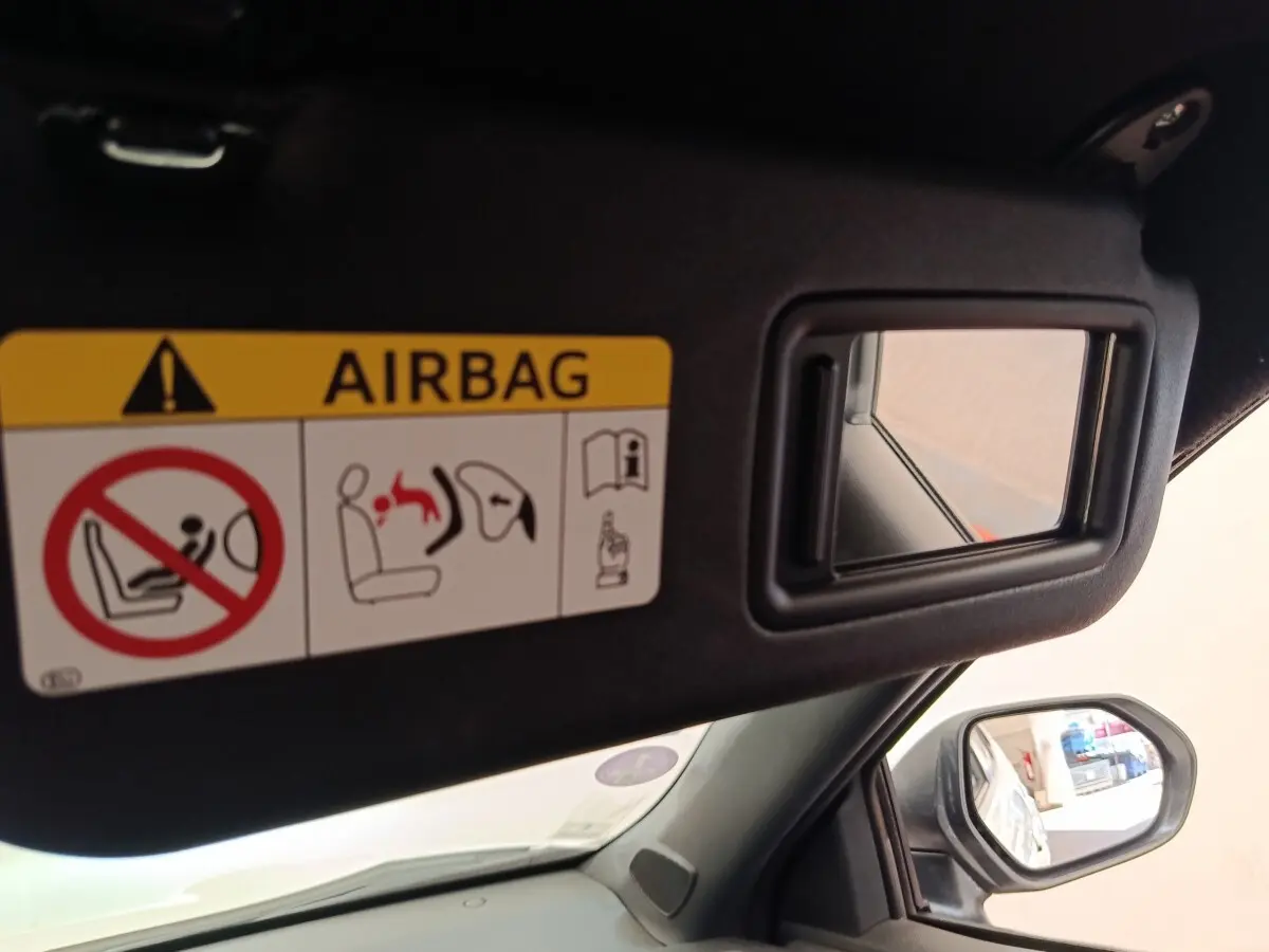 Détail intérieur du pare-soleil côté conducteur avec miroir et avertissement airbag dans une Toyota Yaris Cross blanche.
