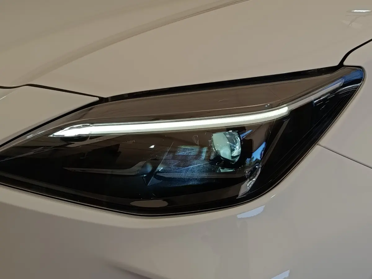 Gros plan sur le phare avant droit LED du Toyota Yaris Cross blanc, soulignant son design moderne et épuré.