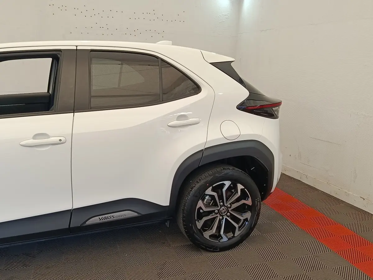 Vue côté arrière droit de la Toyota Yaris Cross blanche, soulignant les jantes alliage et les détails noirs autour des passages de roue.