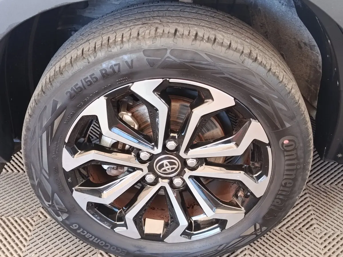 Gros plan sur la roue avant droite avec jante alliage noire et argentée du Toyota Yaris Cross blanc 2022.