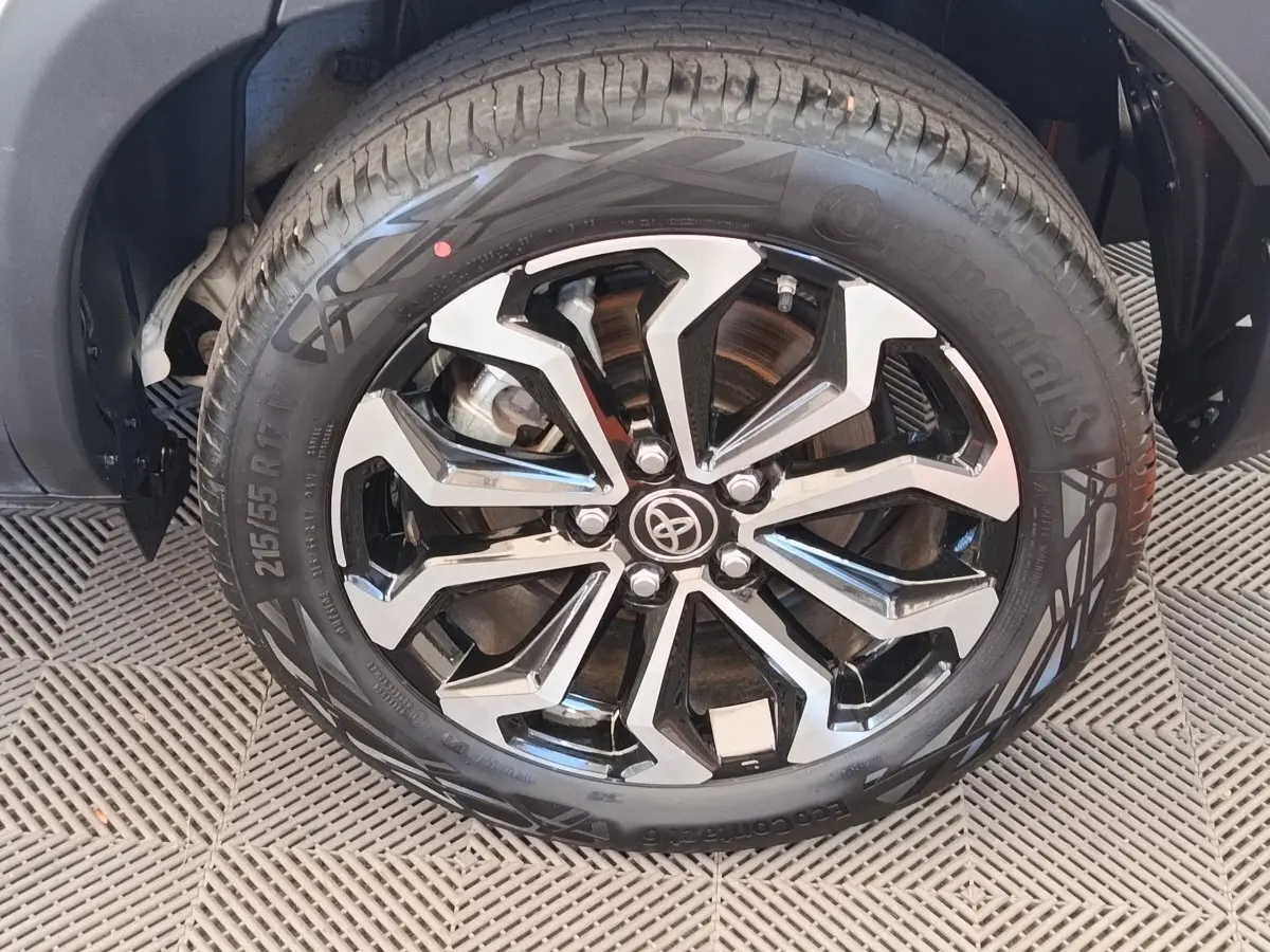 Gros plan sur la jante noire et argentée avec logo Toyota d’un pneu Continental monté sur une Toyota Yaris Cross blanche.