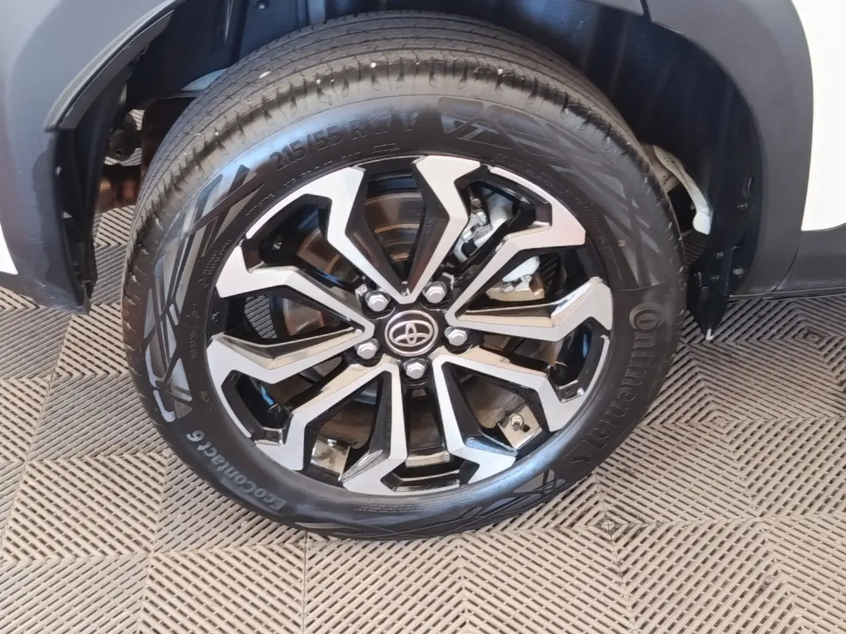 Gros plan sur la roue avant droite de la Toyota Yaris Cross blanche, mettant en valeur la jante noire et argentée au design moderne.