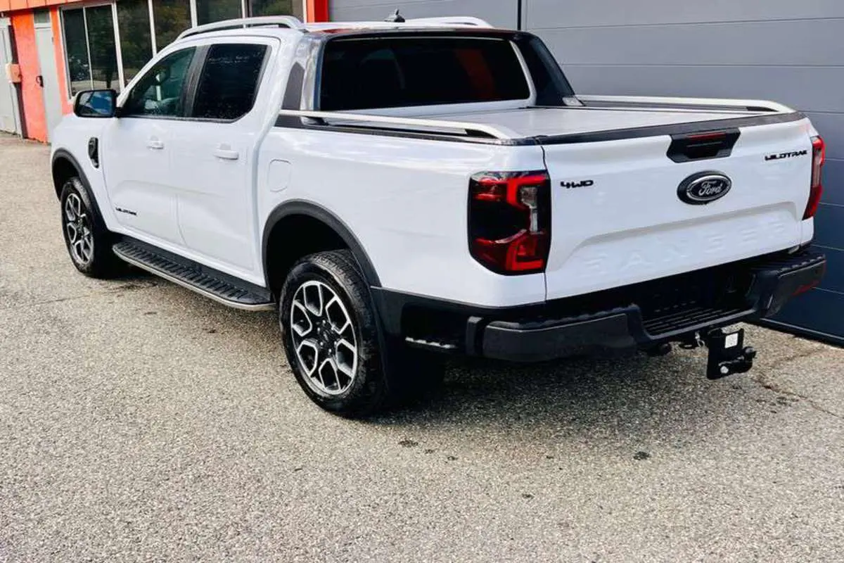 Ford Ranger Wildtrak blanc vu en 3/4 arrière droit, avec jantes alu 20 pouces et attelage visible.