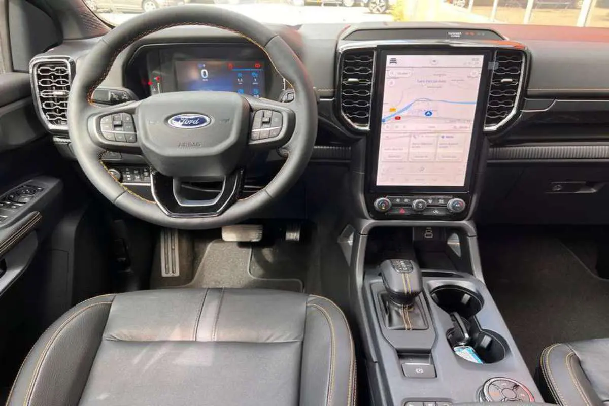 Vue intérieure du tableau de bord du Ford Ranger Wildtrak 2026, volant cuir noir et écran tactile central vertical.