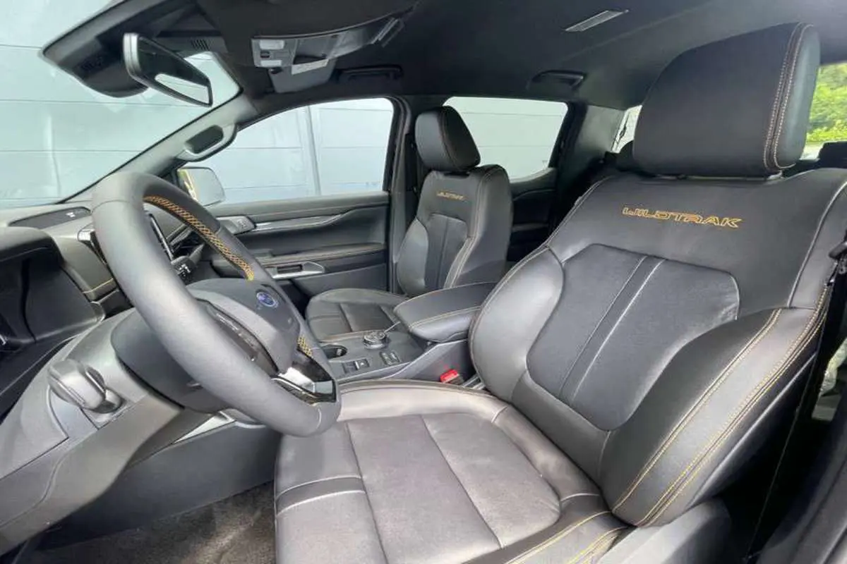 Vue intérieure côté conducteur du Ford Ranger Wildtrak 2026 avec sièges cuir noirs brodés et volant multifonctions.