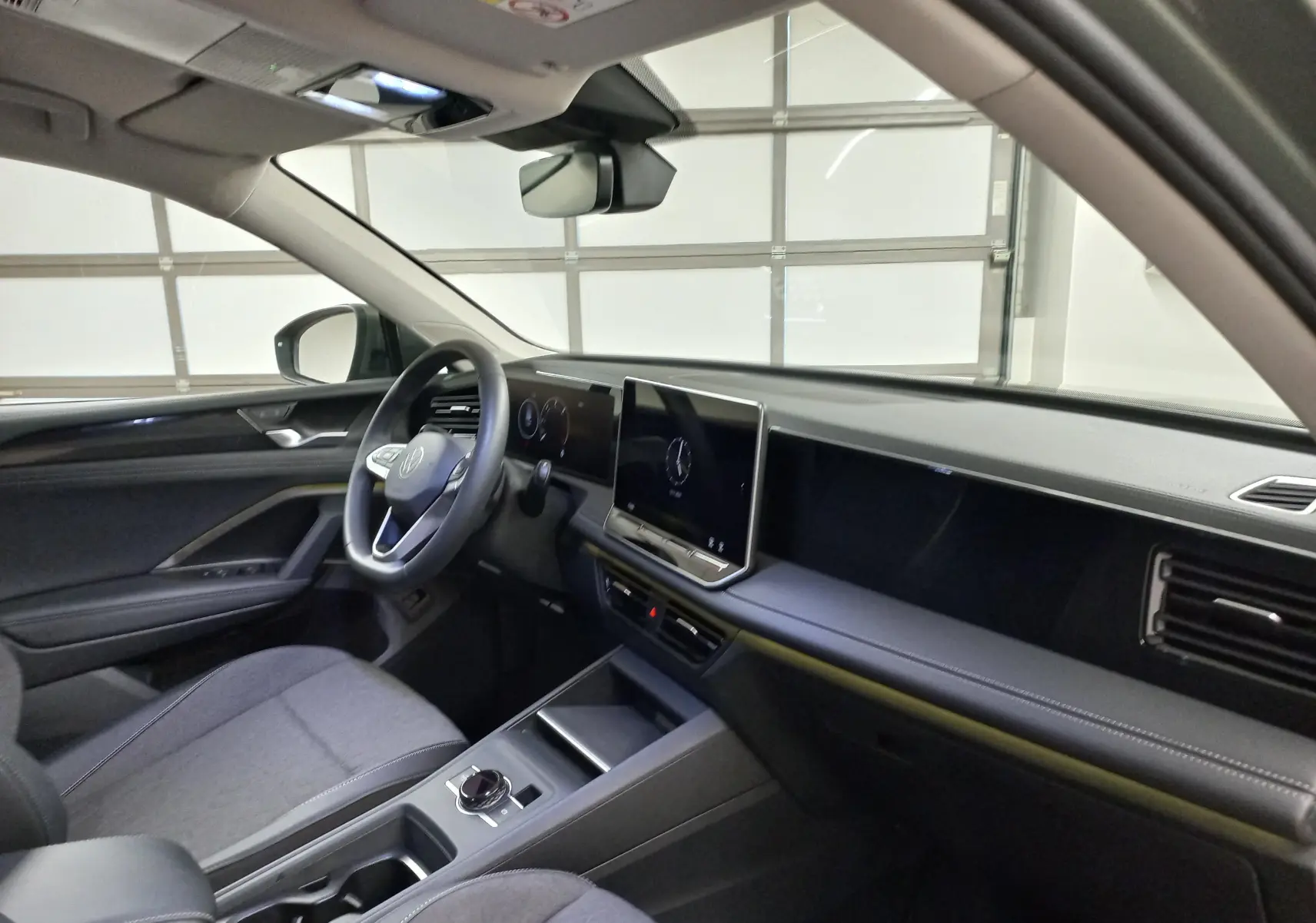 Intérieur du Volkswagen Tiguan 2025 vu côté conducteur, tableau de bord moderne avec écran tactile et volant multifonction.