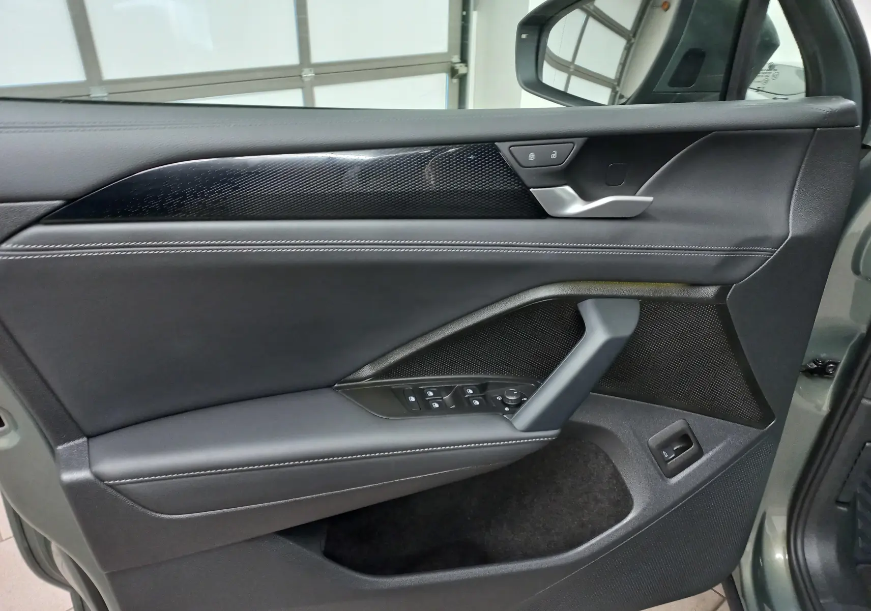 Gros plan sur la porte avant gauche du Volkswagen Tiguan 2025 avec garniture noire et boutons de commande intégrés.