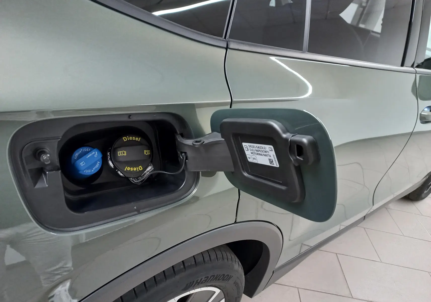 Trappe à carburant ouverte côté gauche d'un Volkswagen Tiguan Vert Cipressino 2025, détail bouchon diesel et AdBlue.