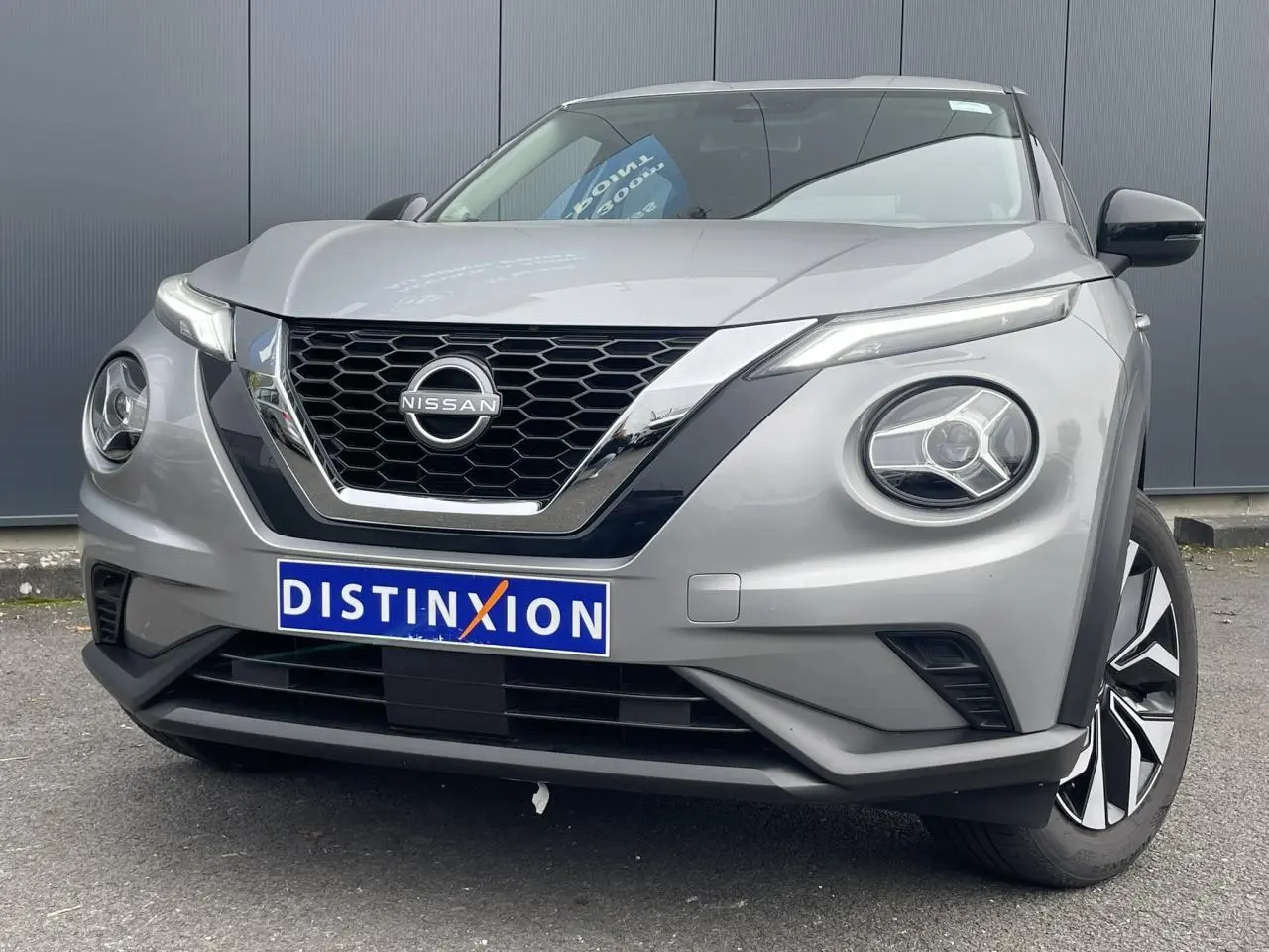 Vue avant rapprochée du Nissan Juke 2024 gris silver avec calandre noire et phares LED ronds distinctifs.