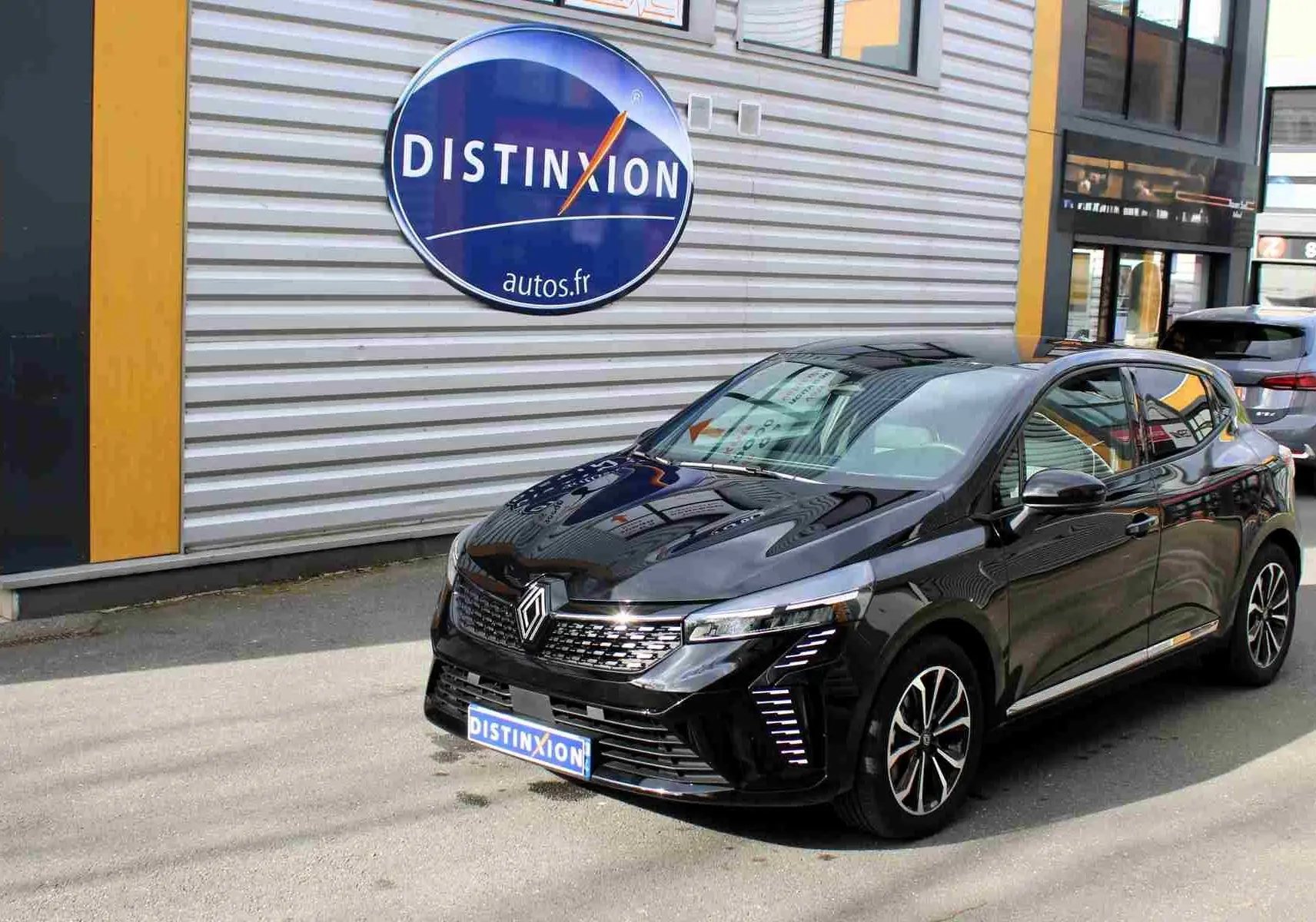 Renault Clio hybride noire étoile métal vue 3/4 avant droit, avec calandre distinctive et jantes bicolores.