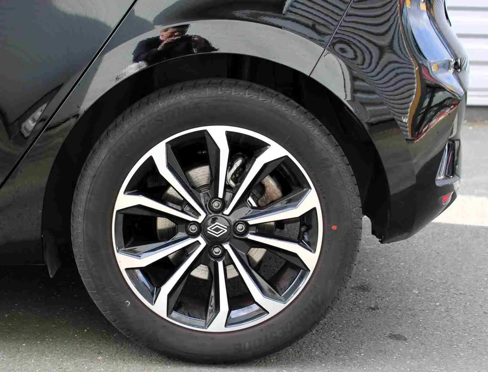 Gros plan sur la roue arrière droite d'une Renault Clio noire étoile métal avec jante alliage bicolore moderne.