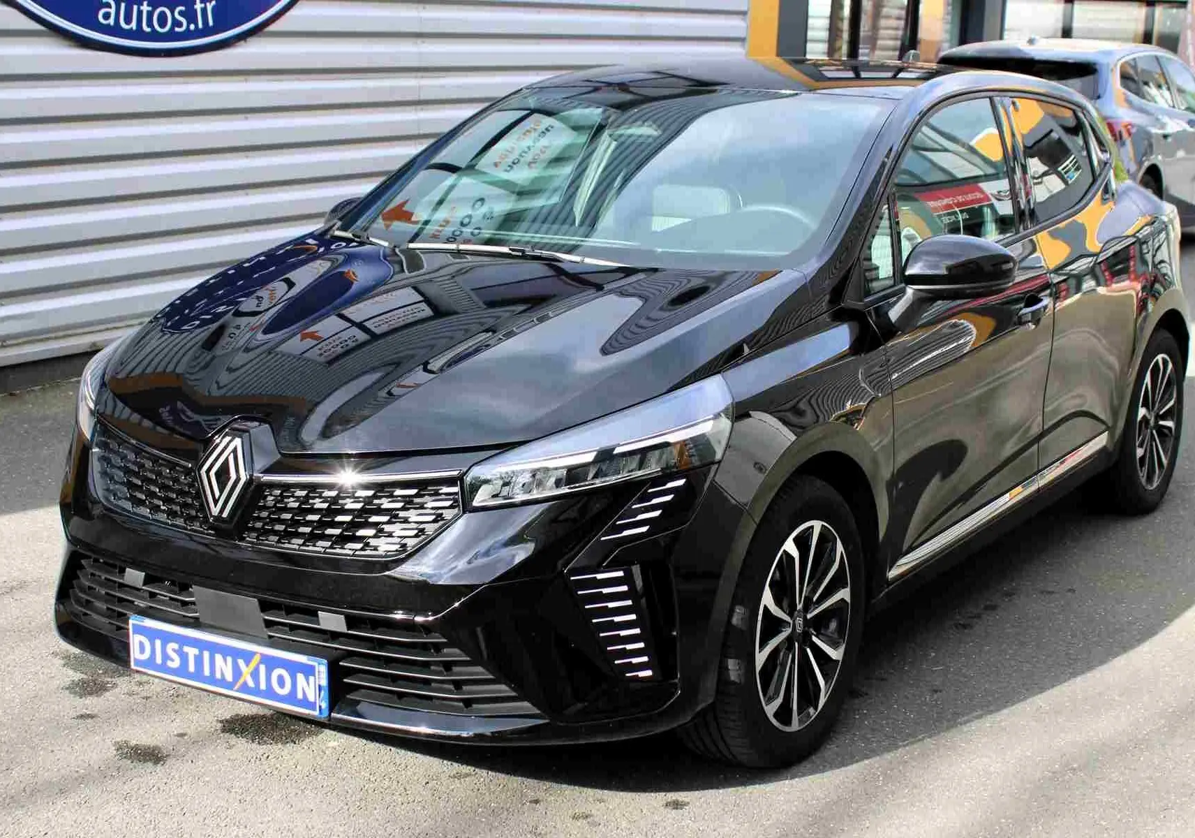 Renault Clio 2025 noir étoile métal en 3/4 avant droit, avec calandre moderne et feux LED distinctifs allumés.