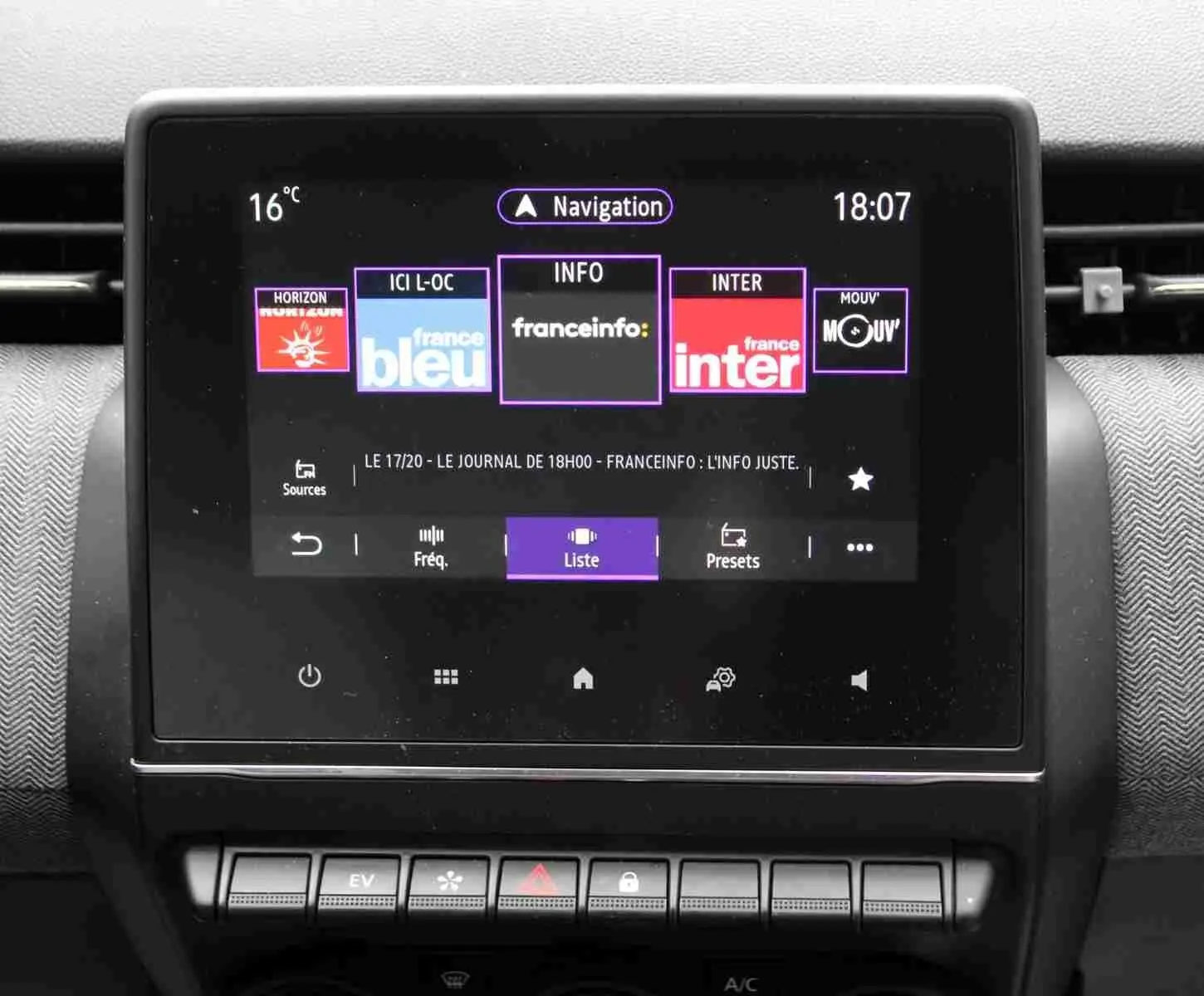 Écran tactile central de la Renault Clio 2025 affichant les stations radio, avec tableau de bord gris noir en arrière-plan.