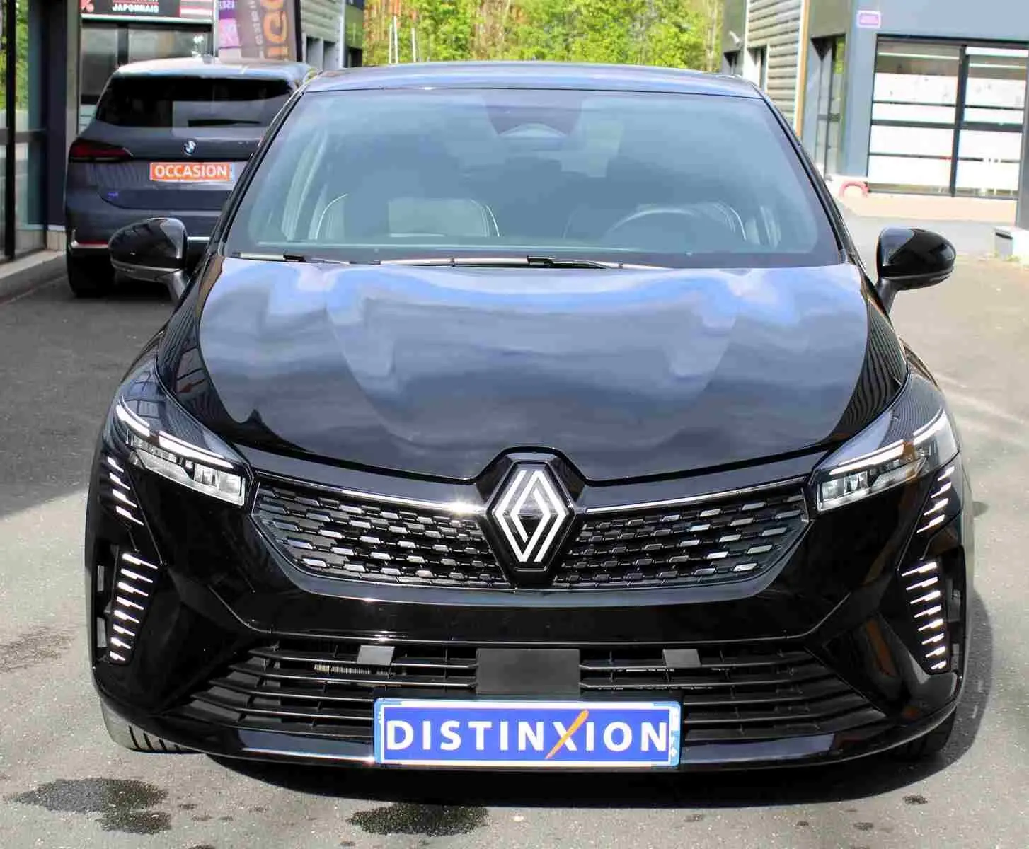 Vue avant d'une Renault Clio noire étoile métal 2025 avec calandre moderne et feux LED verticaux allumés.