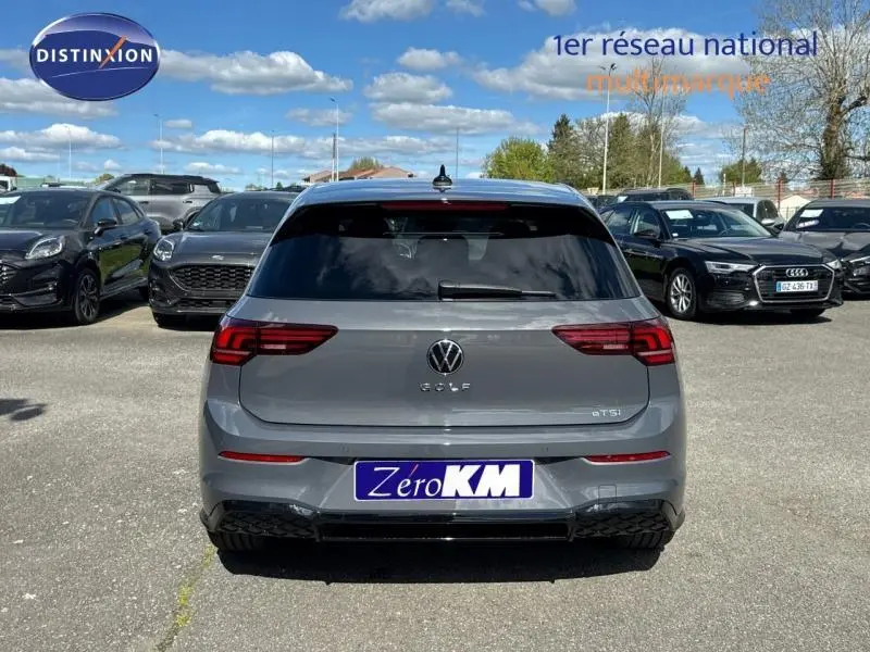 Vue arrière d'une Volkswagen Golf gris lunaire 2026 avec feux LED et lunette arrière surteintée sur parking.