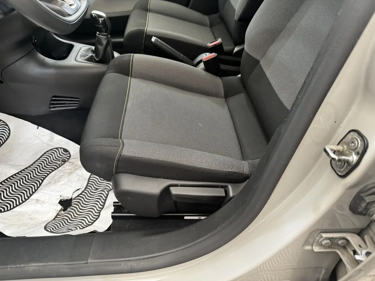 Vue intérieure côté conducteur de la Citroën C3 beige 2021, montrant les sièges avant en tissu gris et noir avec surpiqûres jaunes.