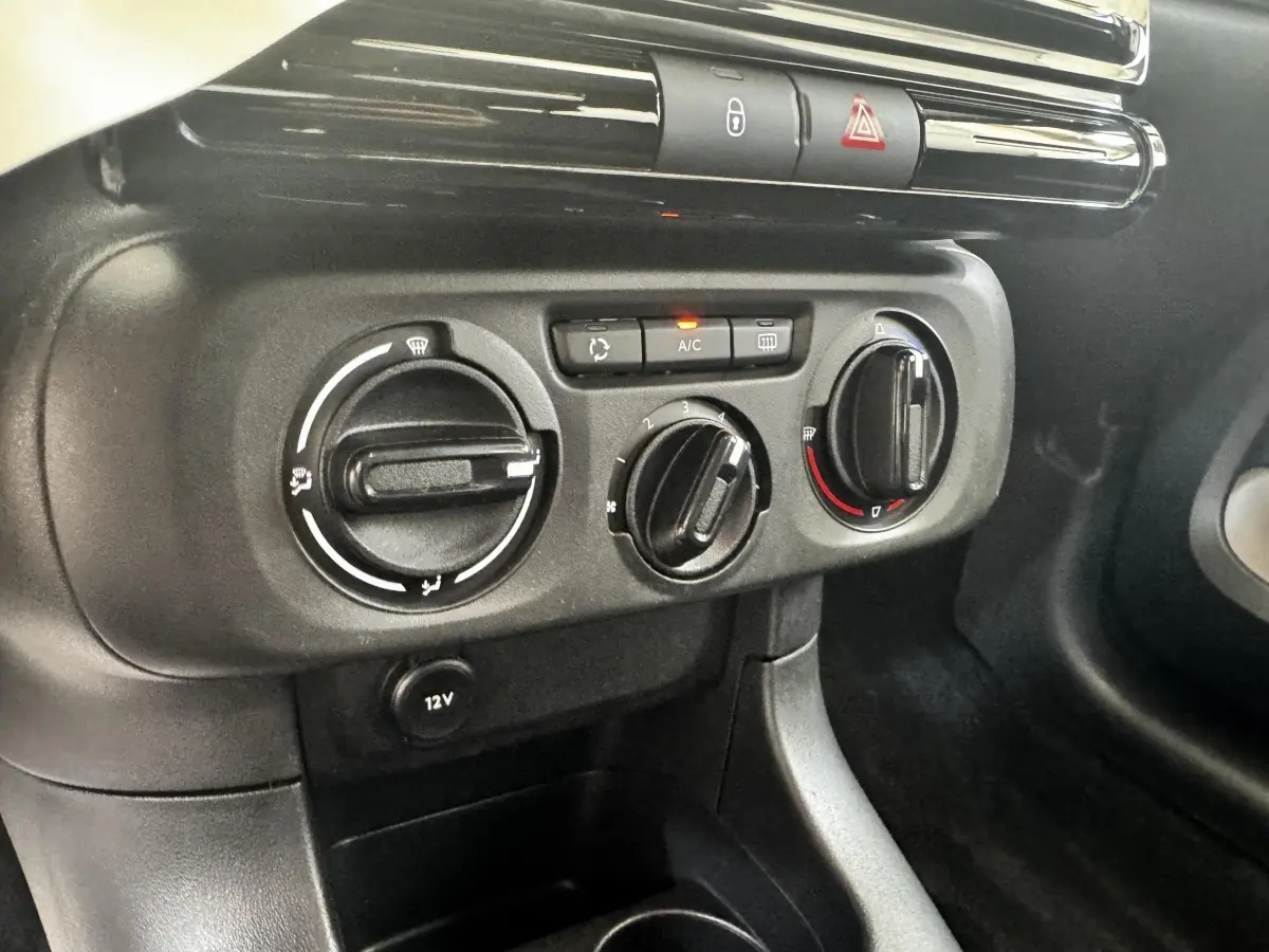 Gros plan sur les commandes de climatisation et prise 12V du tableau de bord intérieur de la Citroën C3 beige.