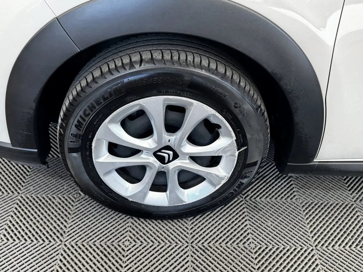 Gros plan sur la roue avant droite d'une Citroën C3 blanche avec jante alliage et pneu Michelin visible.
