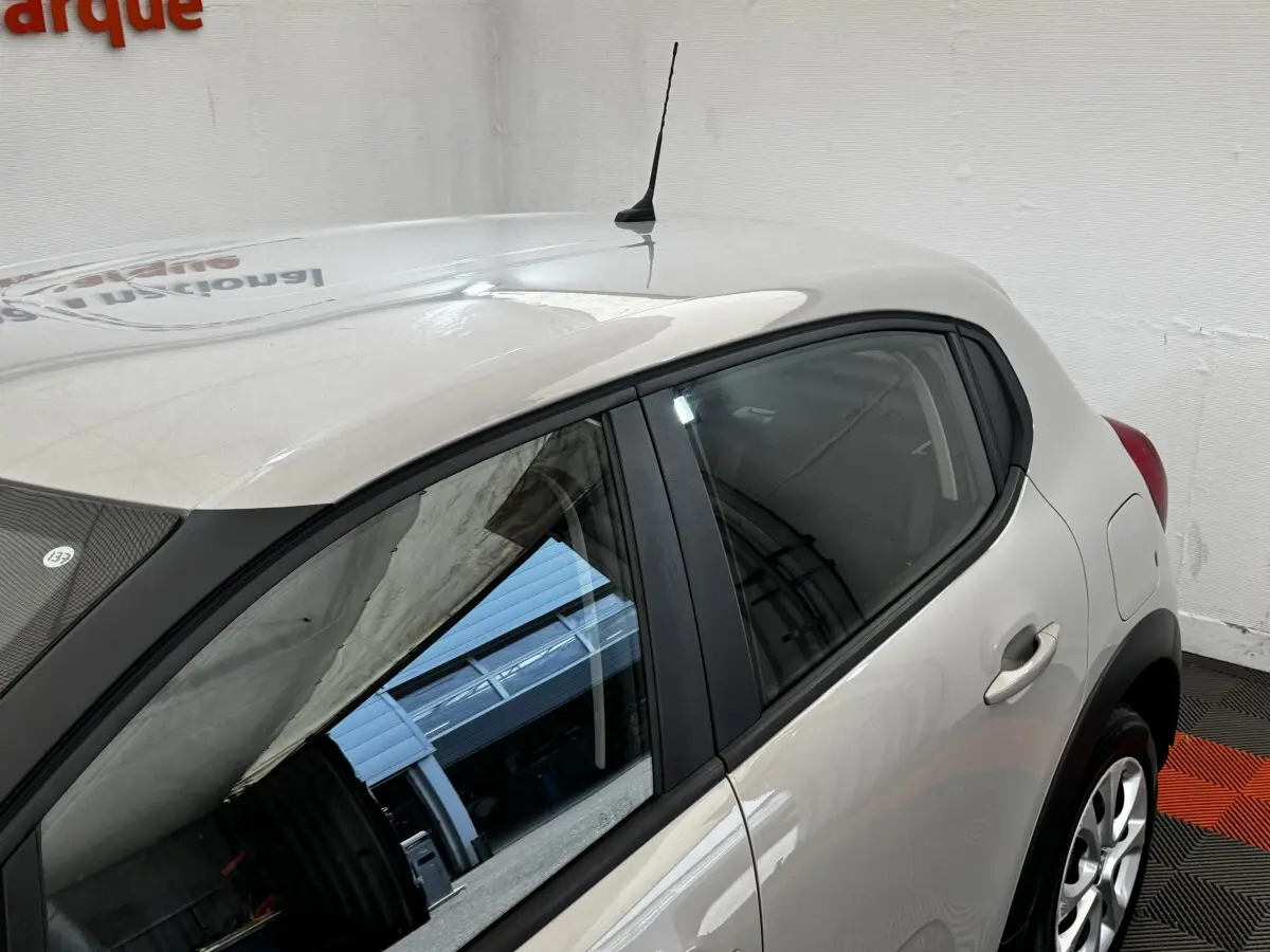 Vue côté droit arrière d'une Citroën C3 beige 2021 avec poignées et jantes visibles en intérieur showroom.