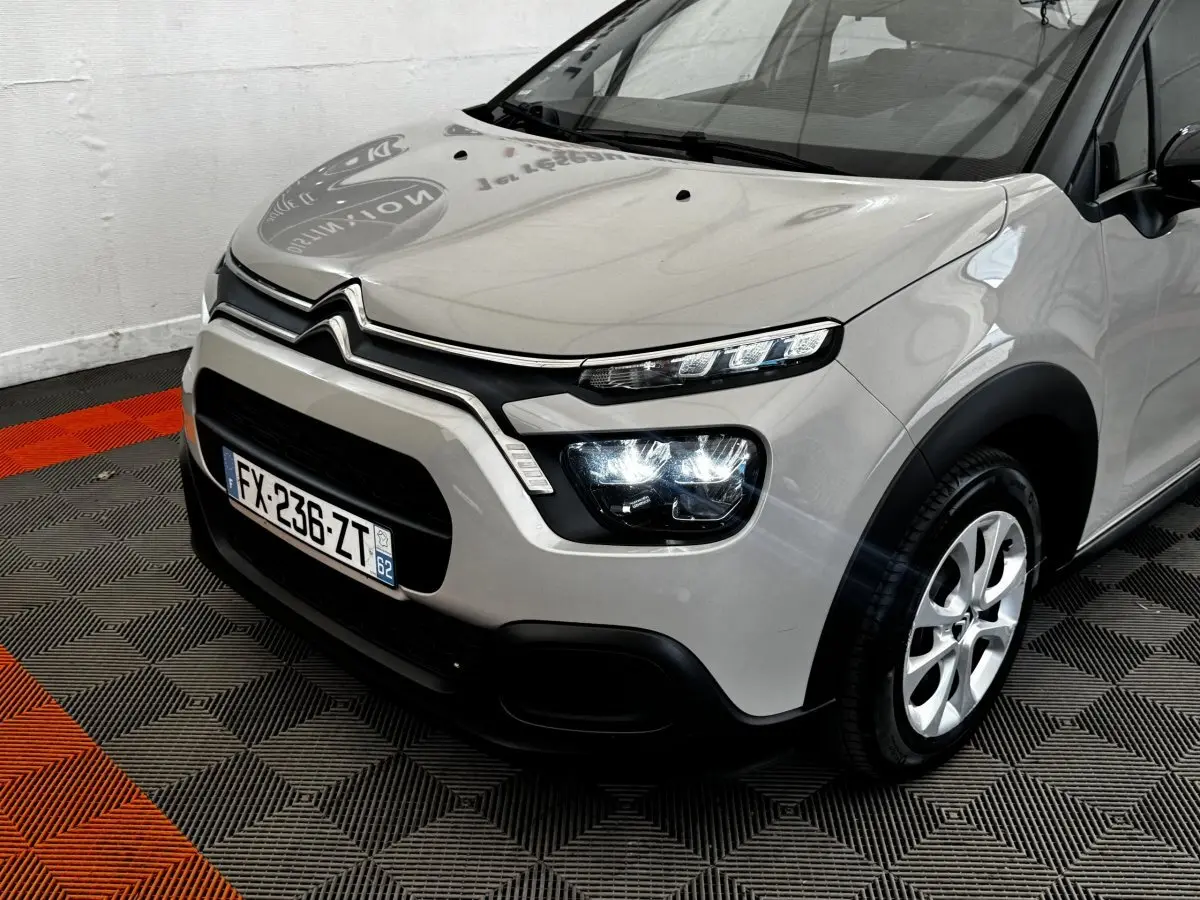 Vue 3/4 avant droit d'une Citroën C3 beige 2021 avec phares LED et calandre noire distinctive.