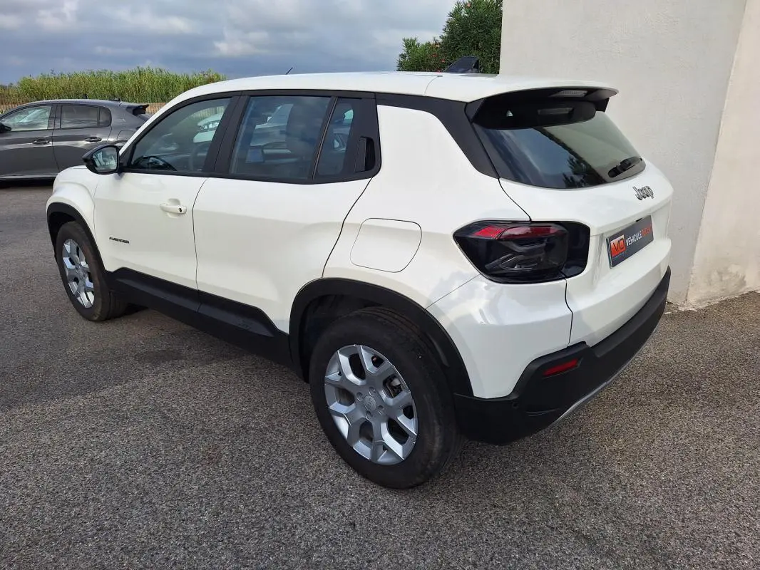 Vue 3/4 arrière droite d'un Jeep Avenger blanc 2025 avec jantes alliage 17 pouces et feux arrière noirs.