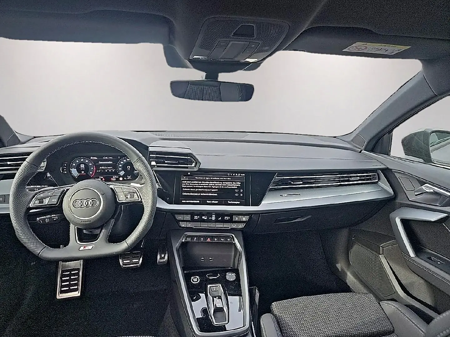 Intérieur Audi A3 Sportback 2026 vu de face, tableau de bord noir avec écran central et volant sport cuir noir.
