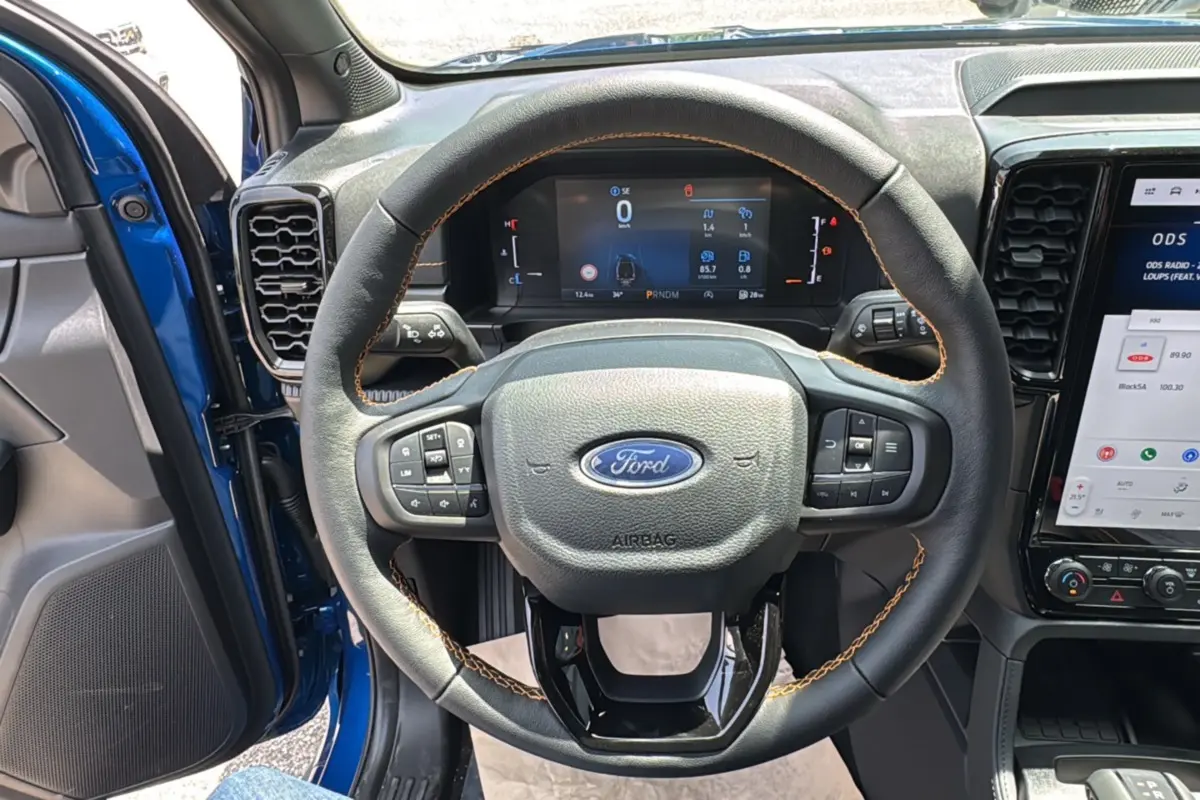 Vue intérieure centrée sur le volant cuir noir avec surpiqûres marron du Ford Ranger Bleu Lightning 2026.