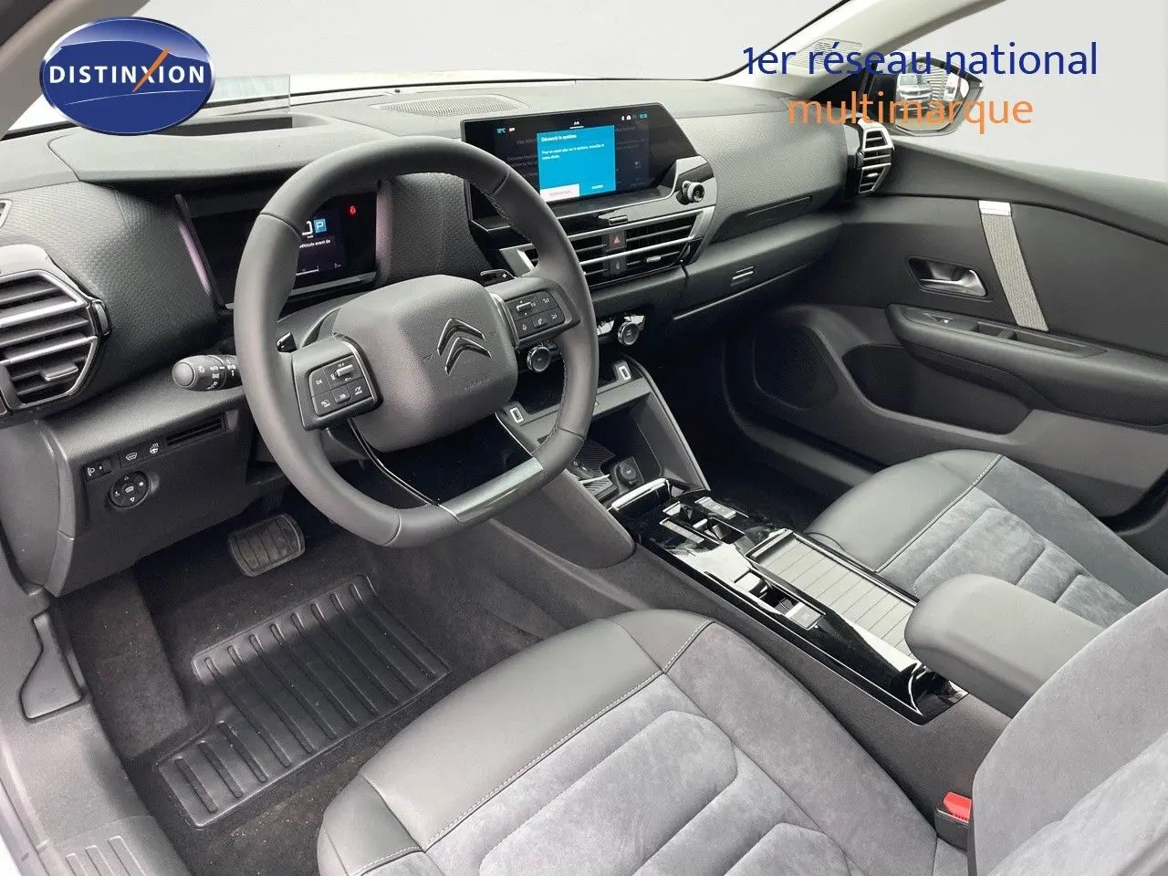 Intérieur moderne de la Citroën C4 2024, vue côté conducteur, avec volant multifonction et sièges cuir gris.