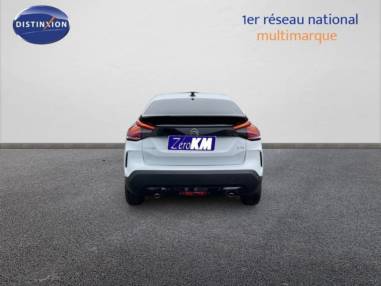 Vue arrière d'une Citroën C4 blanche métal 2024 avec feux LED et double sortie d'échappement visible sur sol gris.