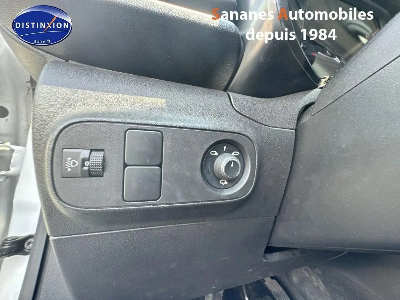 Gros plan sur les commandes d'éclairage et réglage des rétroviseurs côté gauche d'une Citroën C3 blanche 2023.