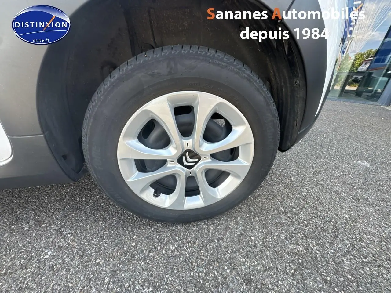 Gros plan sur la roue avant droite d'une Citroën C3 blanche avec jante argentée et élargisseur d'aile noir mat.