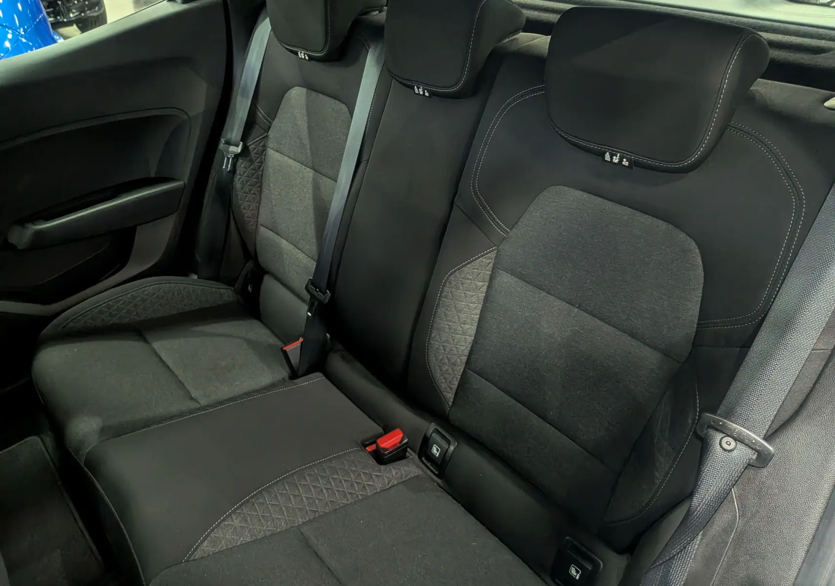 Vue intérieure des sièges arrière en tissu noir et gris de la Renault Clio V Business, avec ceintures de sécurité visibles.